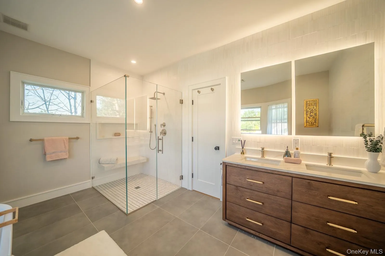 Bathroom with double vanity, a shower stall, plenty of natural light, and tile patterned flooring Bathroom with double vanity, a shower stall, plenty of natural light, and tile patterned flooring