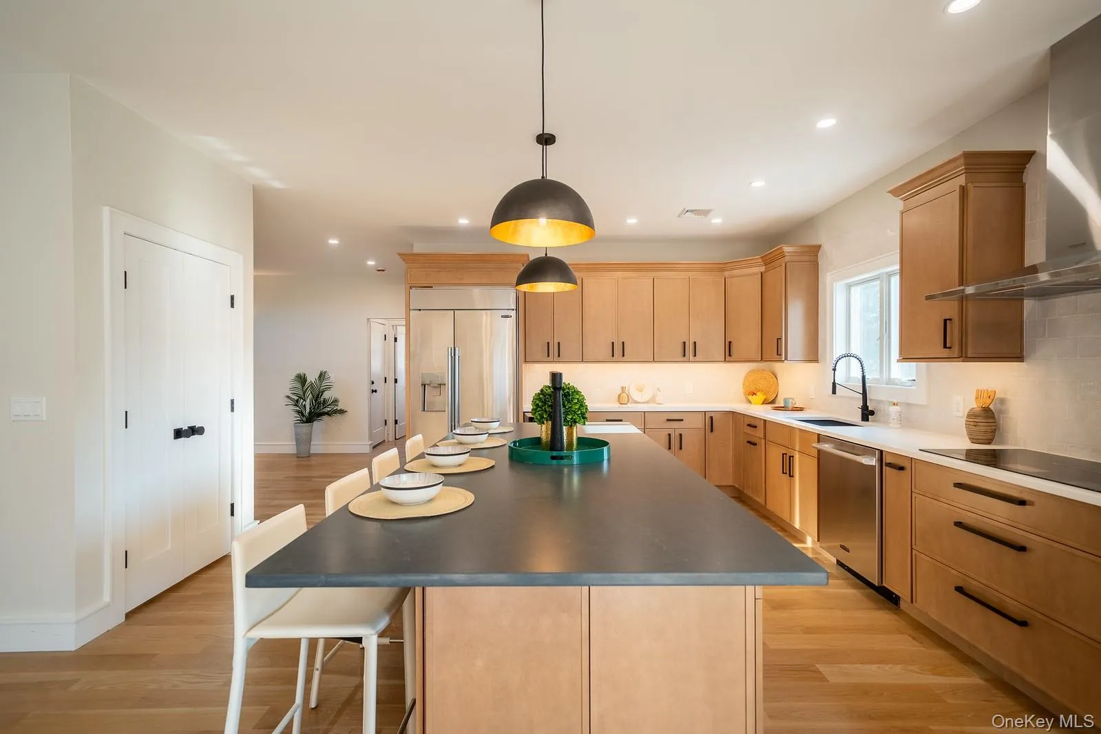 Kitchen featuring wall chimney exhaust hood, light brown cabinetry, light wood finished floors, recessed lighting, and a kitchen island Kitchen featuring wall chimney exhaust hood, light brown cabinetry, light wood finished floors, recessed lighting, and a kitchen island