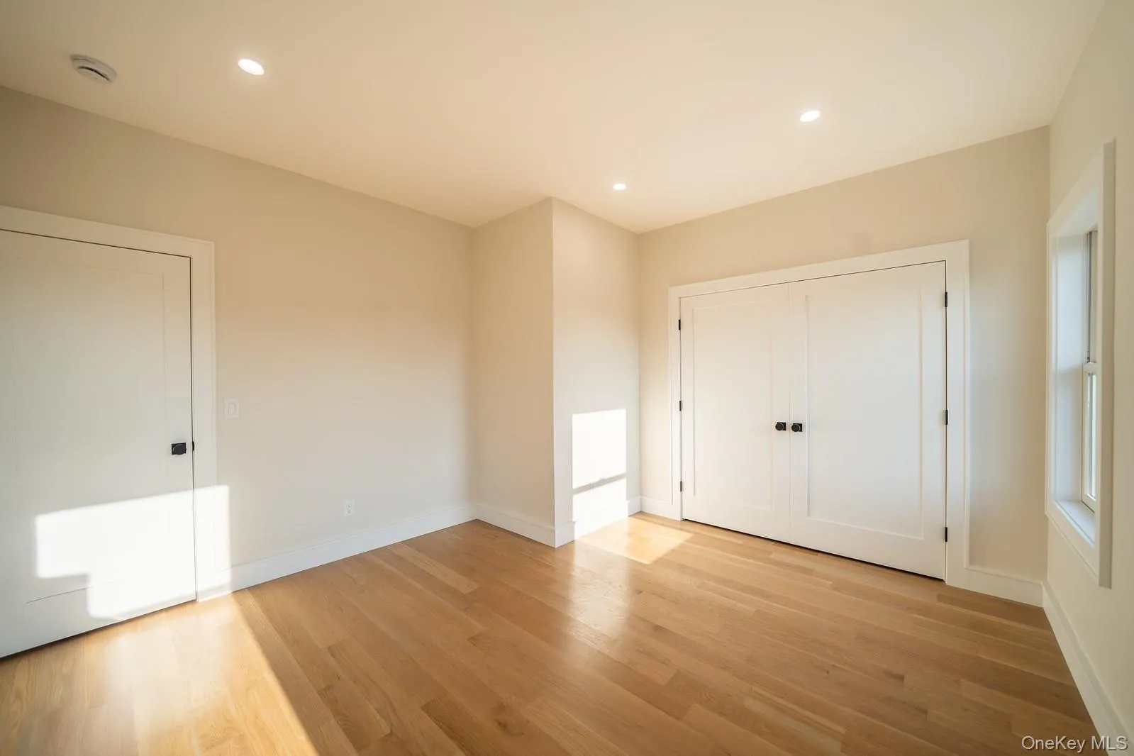 Unfurnished bedroom with light wood finished floors and recessed lighting Unfurnished bedroom with light wood finished floors and recessed lighting