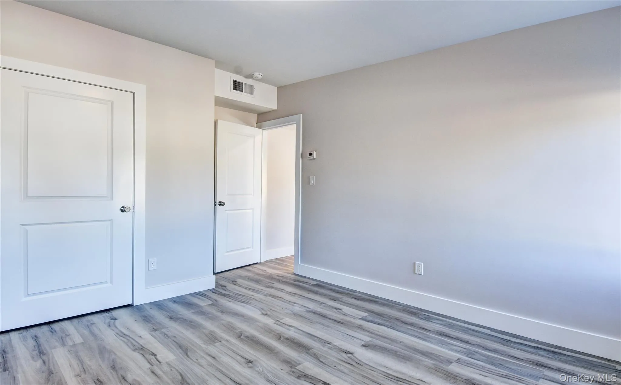 Unfurnished bedroom featuring wood finished floors and a closet Unfurnished bedroom featuring wood finished floors and a closet