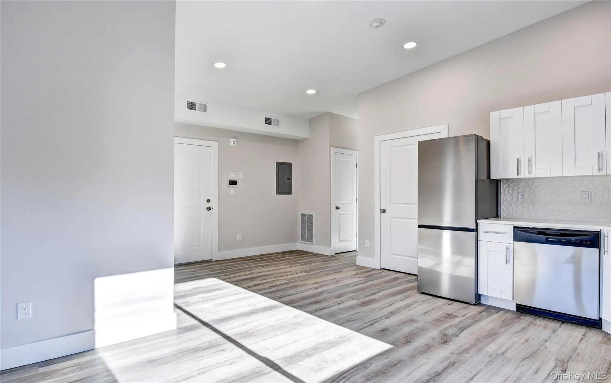 Kitchen featuring white cabinets, appliances with stainless steel finishes, backsplash, light wood finished floors, and recessed lighting Kitchen featuring white cabinets, appliances with stainless steel finishes, backsplash, light wood finished floors, and recessed lighting