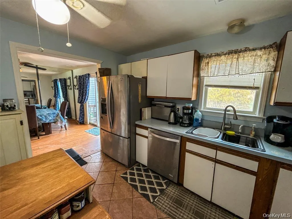 Kitchen featuring ceiling fan, stainless steel appliances, light countertops, and light tile patterned floors Kitchen featuring ceiling fan, stainless steel appliances, light countertops, and light tile patterned floors