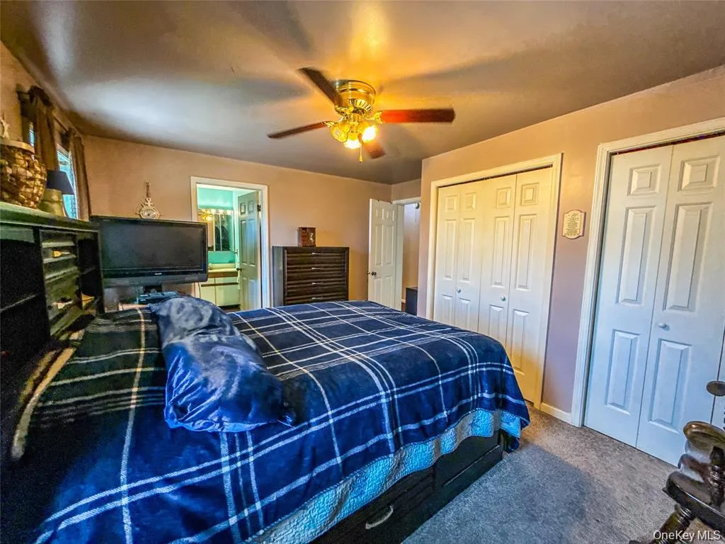Bedroom featuring multiple closets, carpet flooring, a ceiling fan, and ensuite bathroom Bedroom featuring multiple closets, carpet flooring, a ceiling fan, and ensuite bathroom