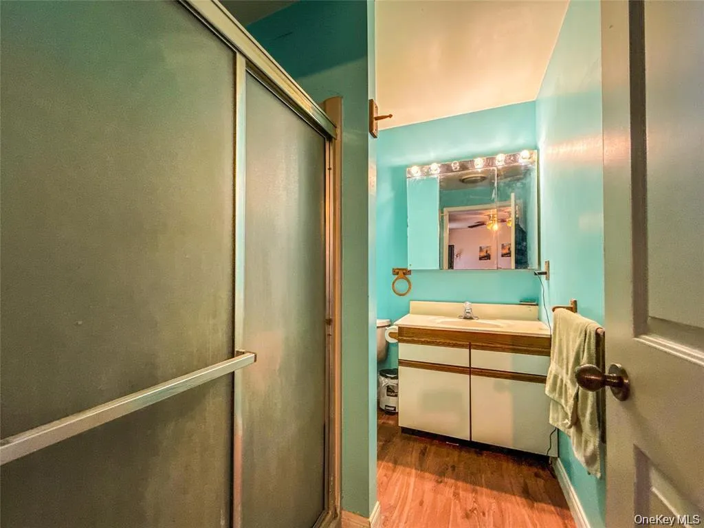 Full bath with vanity, a shower stall, and wood finished floors Full bath with vanity, a shower stall, and wood finished floors