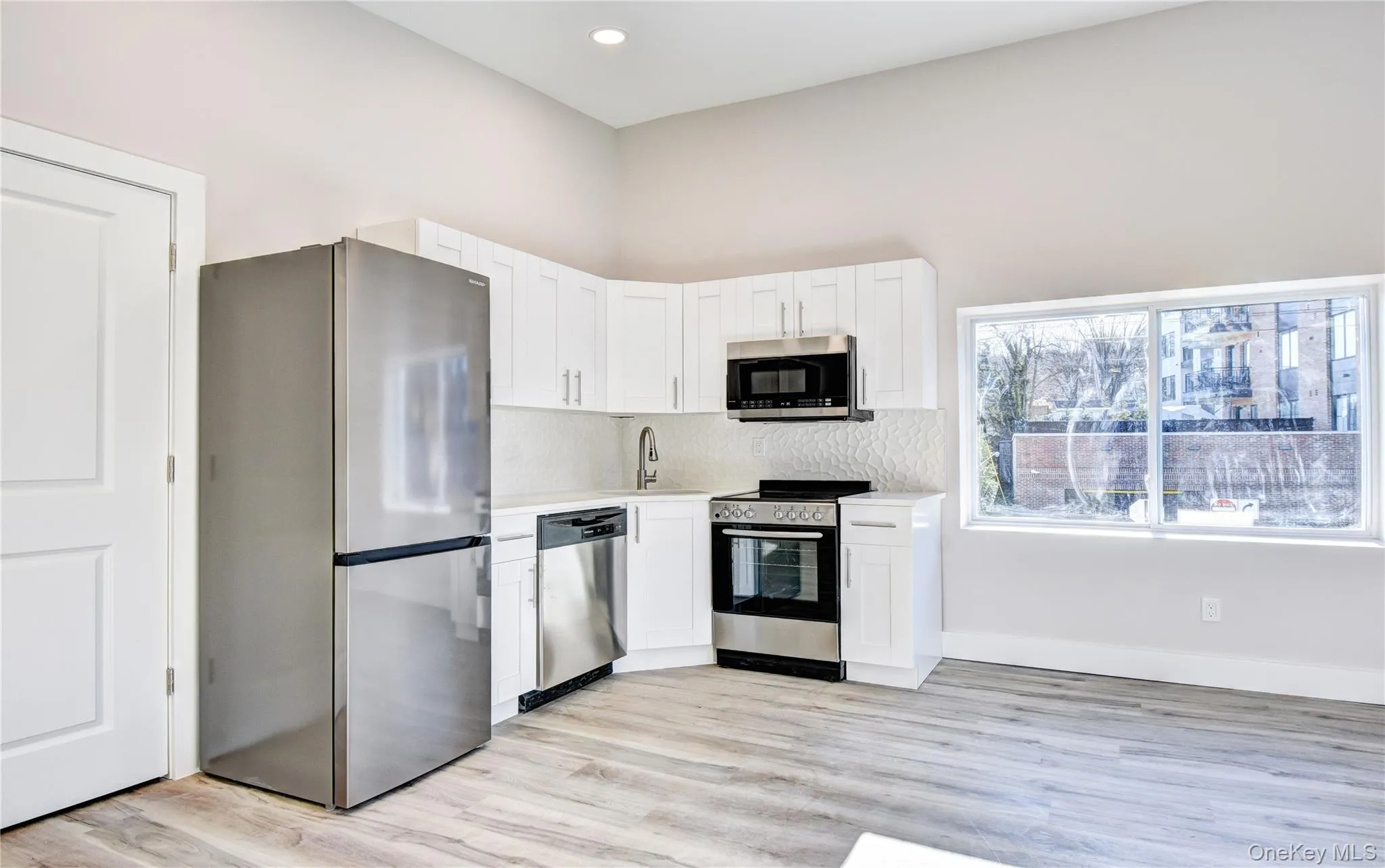 Kitchen with stainless steel appliances, white cabinets, light wood-style flooring, tasteful backsplash, and recessed lighting Kitchen with stainless steel appliances, white cabinets, light wood-style flooring, tasteful backsplash, and recessed lighting