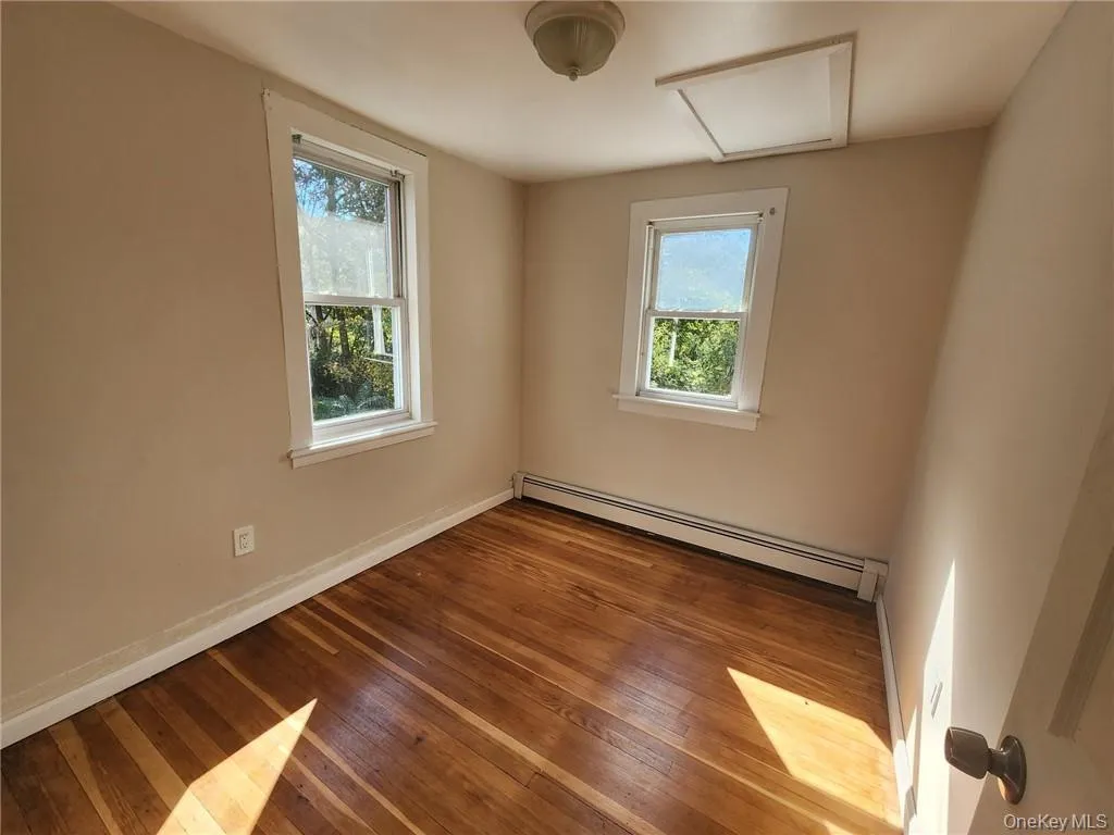 Unfurnished room with attic access, a baseboard radiator, plenty of natural light, and light wood-style flooring Unfurnished room with attic access, a baseboard radiator, plenty of natural light, and light wood-style flooring