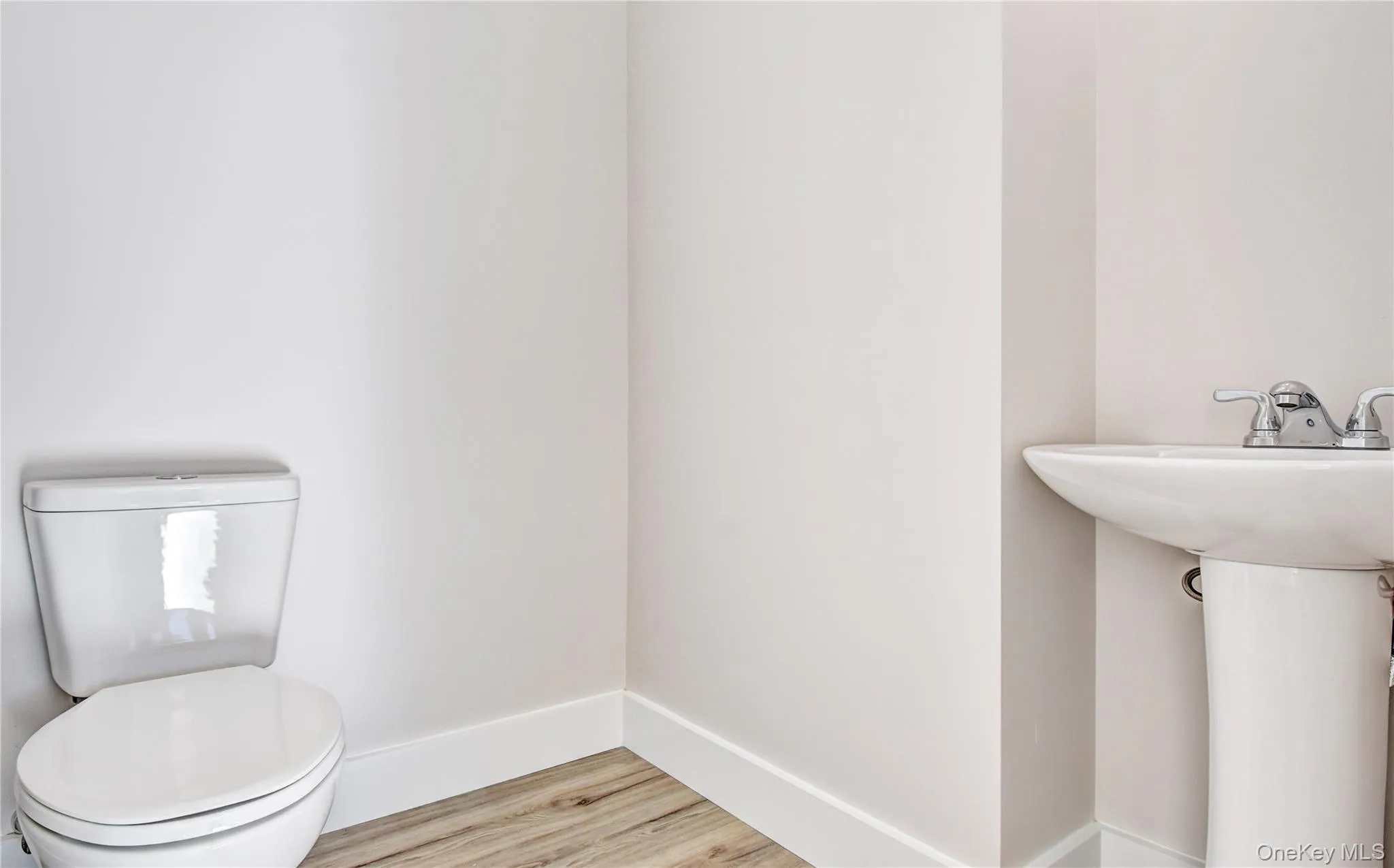 Half bath featuring light wood-style flooring and toilet Half bath featuring light wood-style flooring and toilet