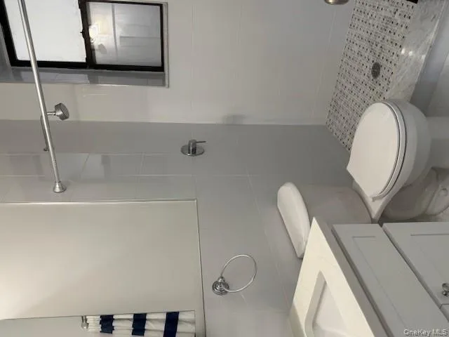 Bathroom featuring a stall shower, tile walls, and vanity Bathroom featuring a stall shower, tile walls, and vanity