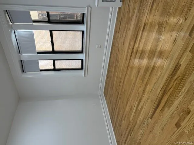 Spare room featuring wood finished floors, healthy amount of natural light, and radiator Spare room featuring wood finished floors, healthy amount of natural light, and radiator