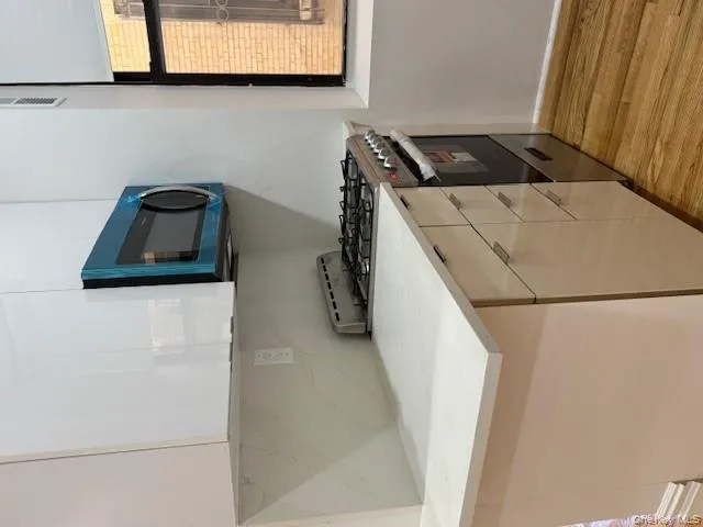 Kitchen featuring stove, modern cabinets, stainless steel microwave, light wood-style flooring, and white cabinets Kitchen featuring stove, modern cabinets, stainless steel microwave, light wood-style flooring, and white cabinets