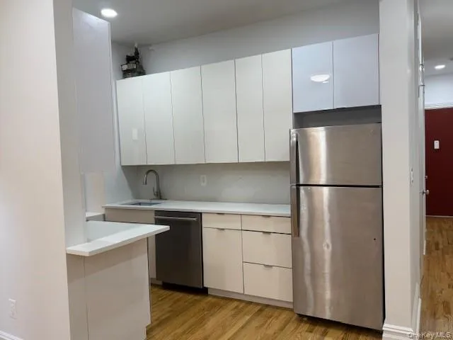 Kitchen with appliances with stainless steel finishes, light wood finished floors, white cabinets, modern cabinets, and recessed lighting Kitchen with appliances with stainless steel finishes, light wood finished floors, white cabinets, modern cabinets, and recessed lighting