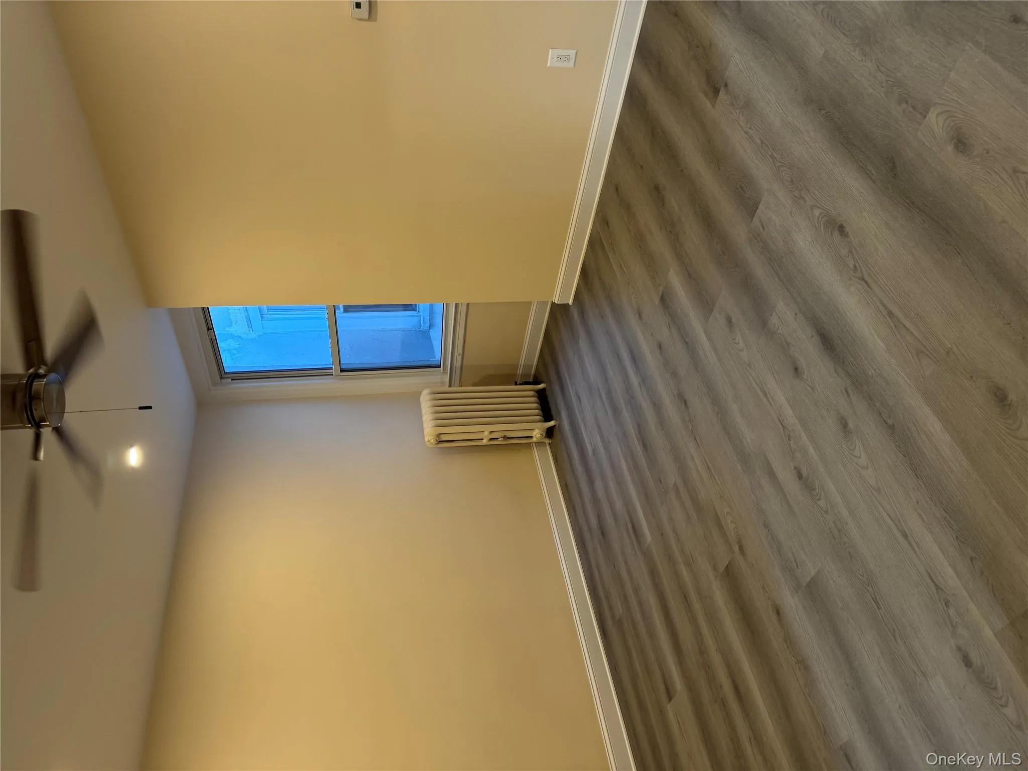 Unfurnished room with radiator heating unit, dark wood-style flooring, a ceiling fan, and recessed lighting Unfurnished room with radiator heating unit, dark wood-style flooring, a ceiling fan, and recessed lighting