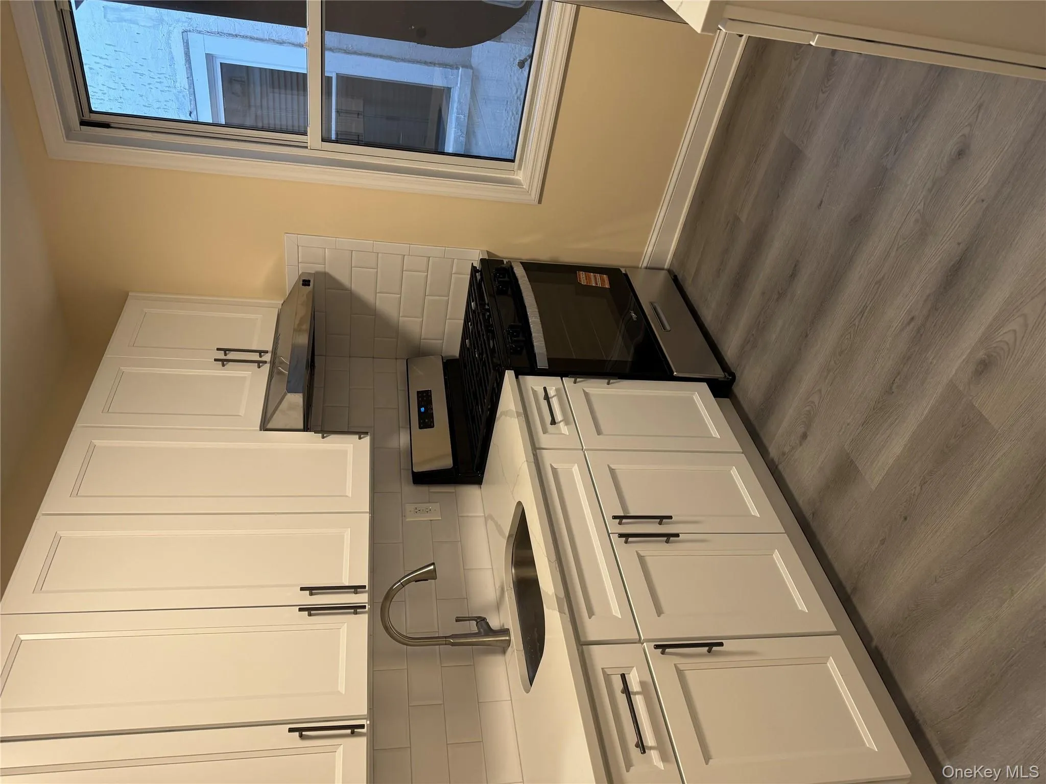Kitchen with gas stove, white cabinetry, and tasteful backsplash Kitchen with gas stove, white cabinetry, and tasteful backsplash