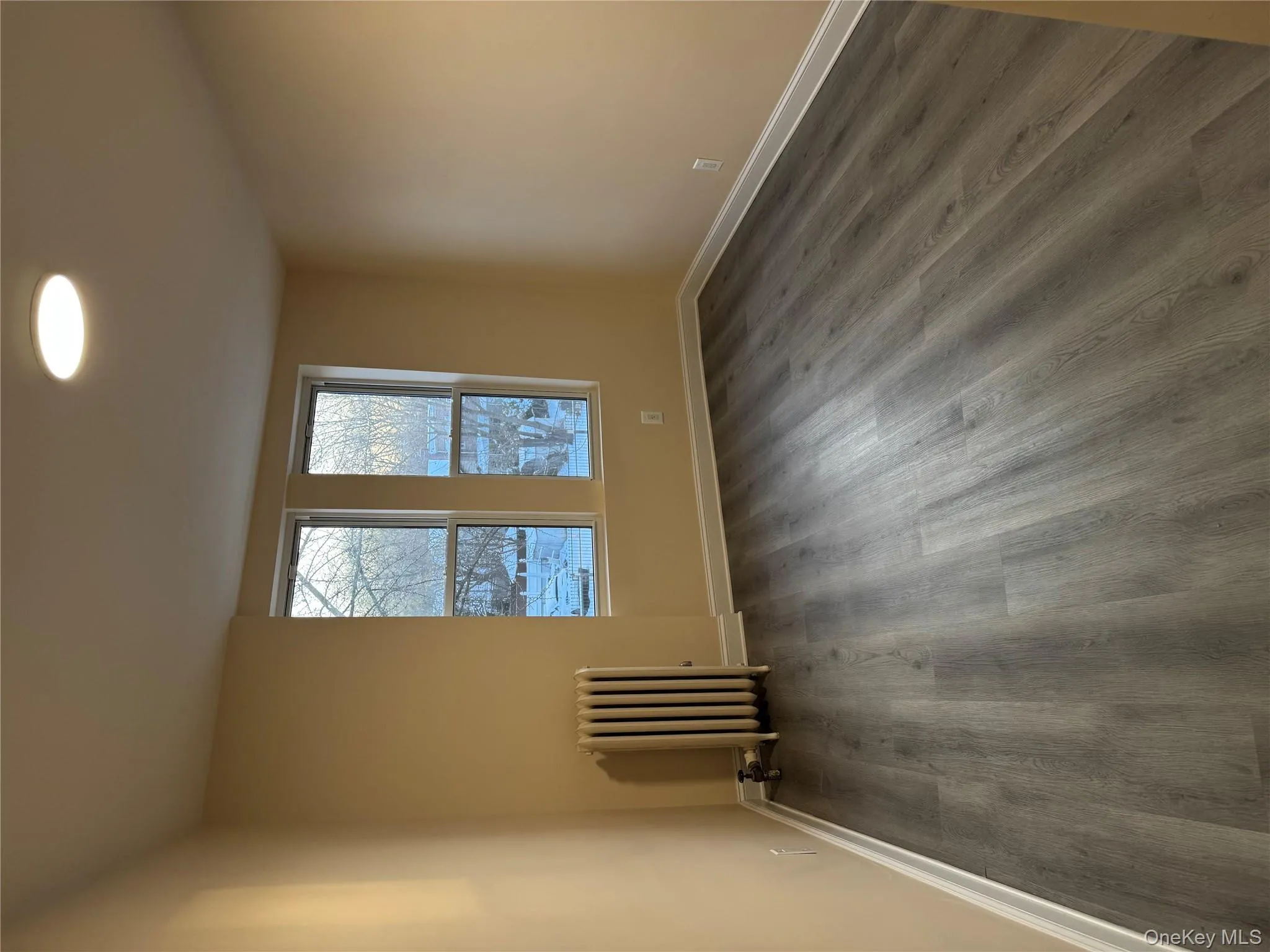 Unfurnished room with radiator heating unit and dark wood-style floors Unfurnished room with radiator heating unit and dark wood-style floors