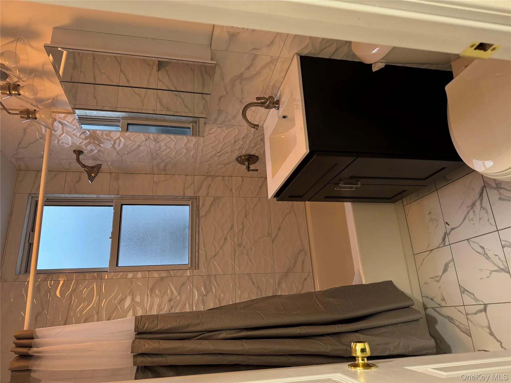 Bathroom with shower / bath combination with curtain, light marble finish flooring, vanity, and tile walls Bathroom with shower / bath combination with curtain, light marble finish flooring, vanity, and tile walls