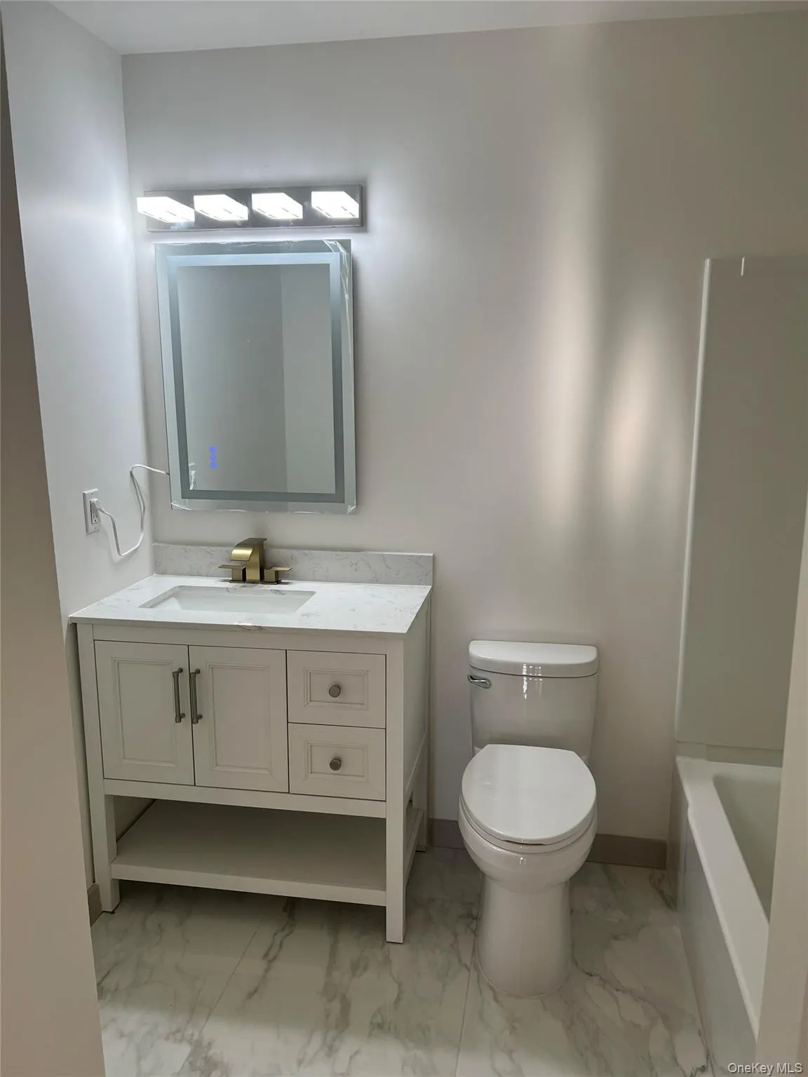 Bathroom with light marble finish floors, a tub to relax in, and vanity Bathroom with light marble finish floors, a tub to relax in, and vanity