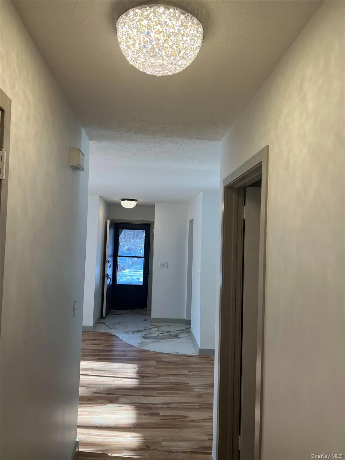 Corridor featuring a textured ceiling and wood finished floors Corridor featuring a textured ceiling and wood finished floors