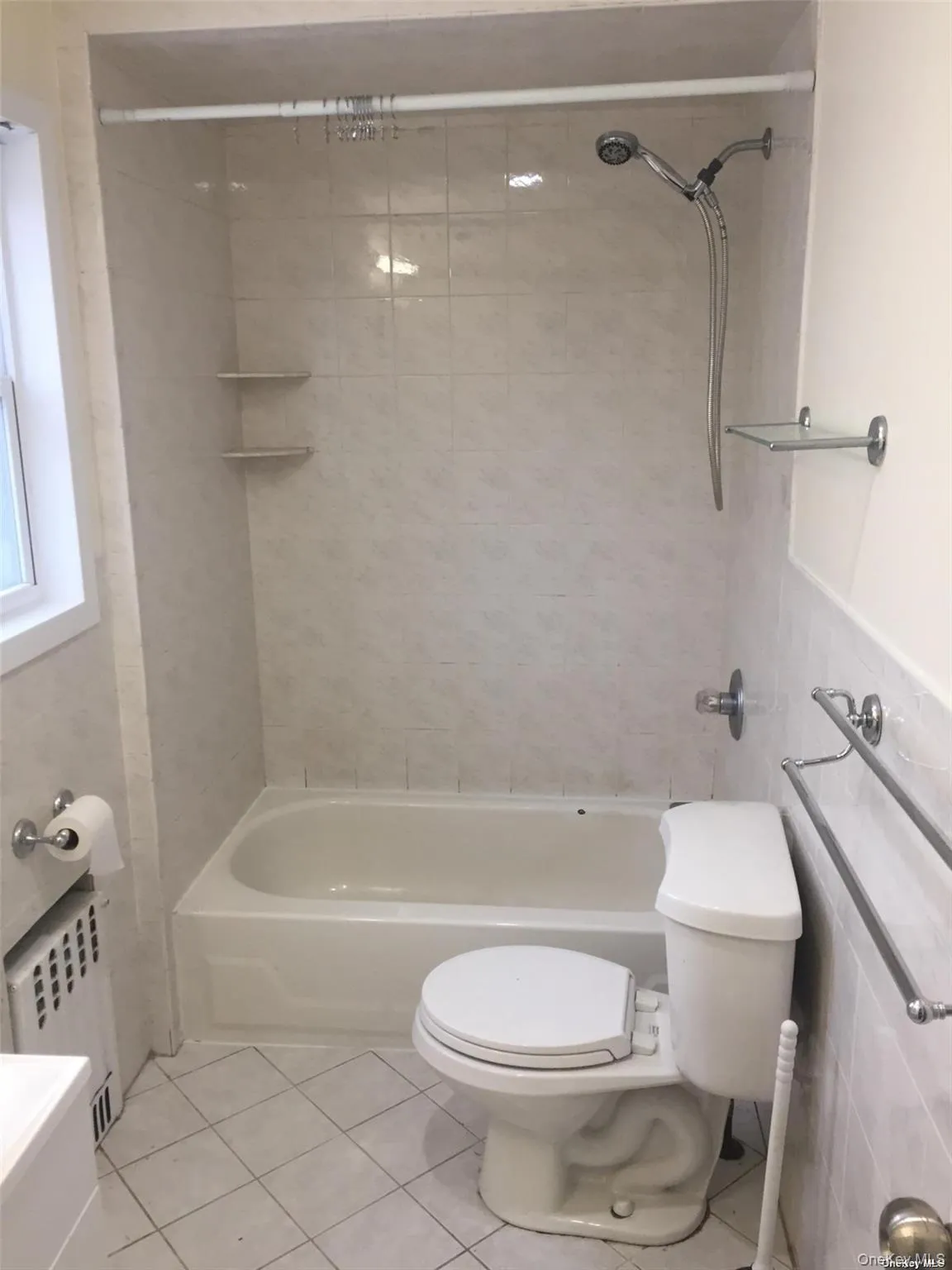 Bathroom featuring radiator heating unit, shower / bathtub combination, tile walls, and light tile patterned floors Bathroom featuring radiator heating unit, shower / bathtub combination, tile walls, and light tile patterned floors