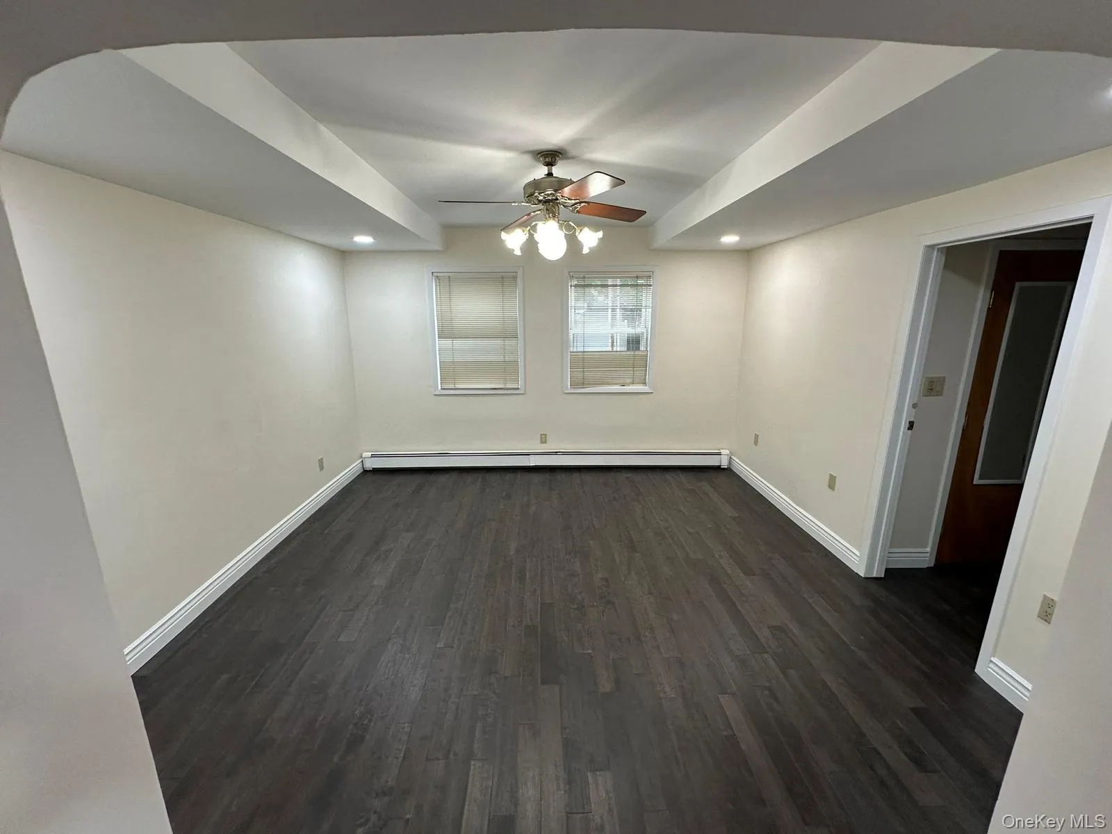 Unfurnished room featuring dark wood-style flooring, a ceiling fan, recessed lighting, and baseboard heating Unfurnished room featuring dark wood-style flooring, a ceiling fan, recessed lighting, and baseboard heating