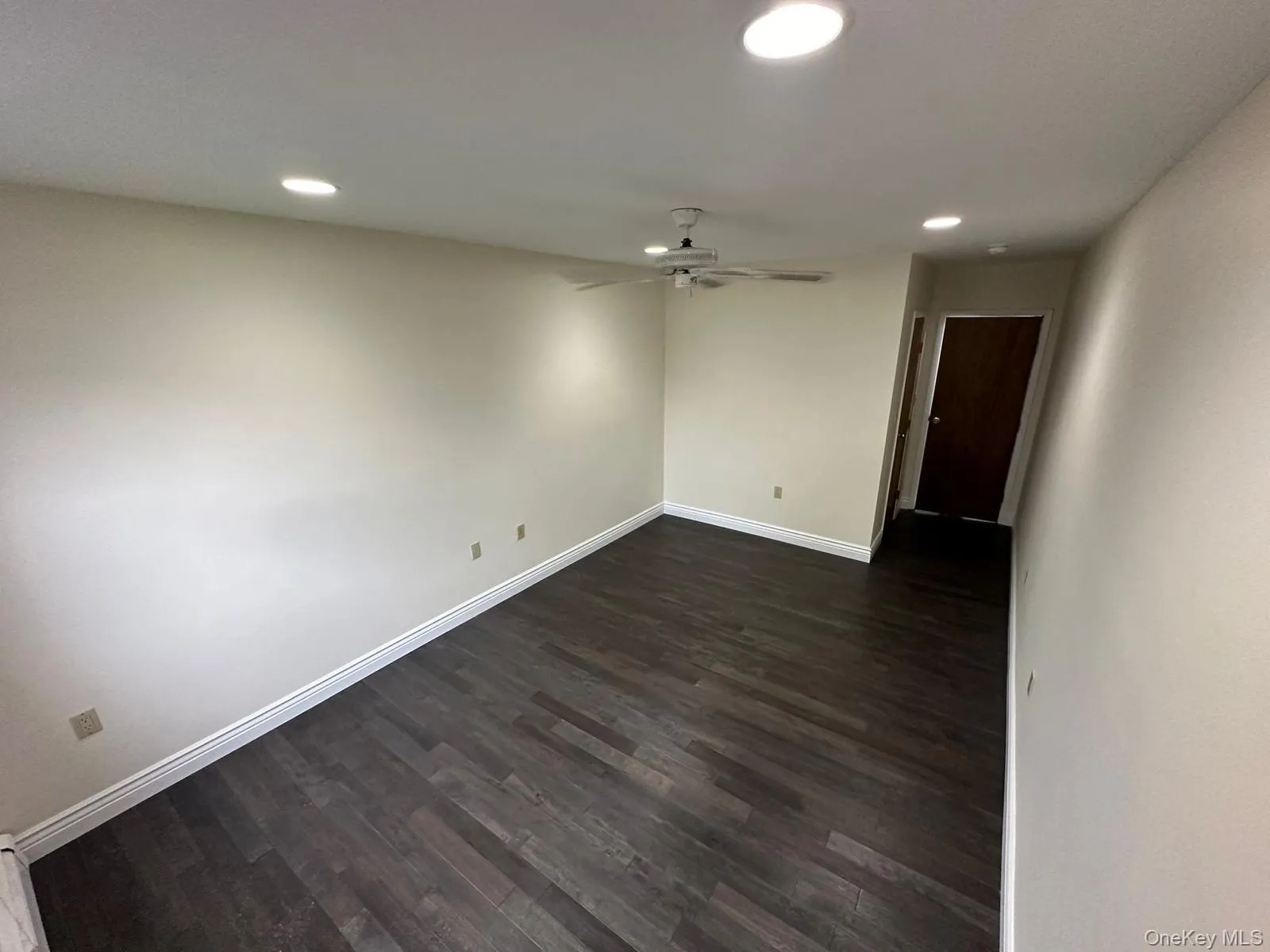 Empty room with dark wood-style floors, ceiling fan, and recessed lighting Empty room with dark wood-style floors, ceiling fan, and recessed lighting