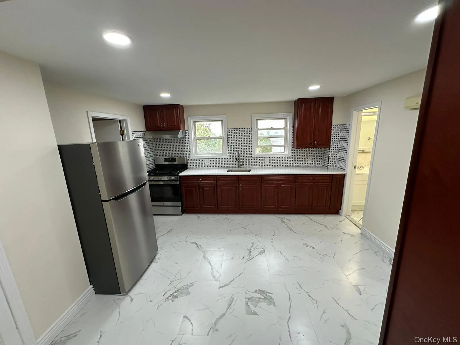 Kitchen with light countertops, stainless steel appliances, light marble finish flooring, decorative backsplash, and recessed lighting Kitchen with light countertops, stainless steel appliances, light marble finish flooring, decorative backsplash, and recessed lighting
