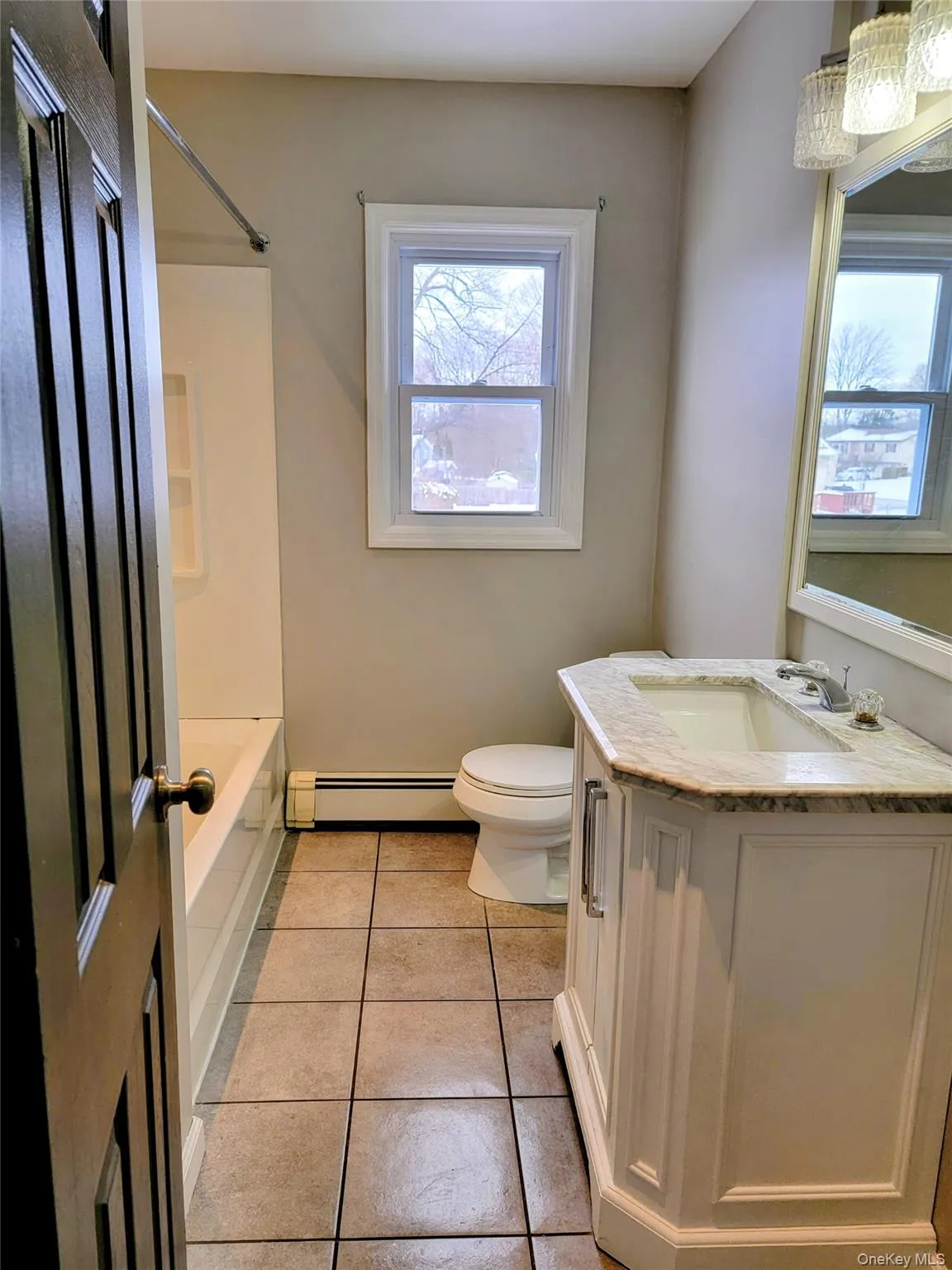 Full bath with vanity, light tile patterned flooring, a baseboard radiator, and bathing tub / shower combination Full bath with vanity, light tile patterned flooring, a baseboard radiator, and bathing tub / shower combination