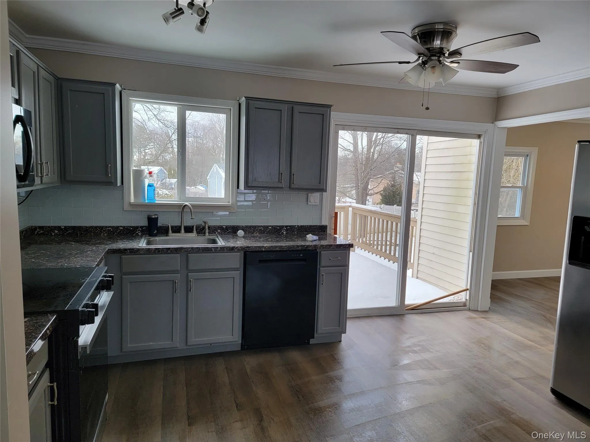 Kitchen with gray cabinets, range with electric stovetop, dishwasher, decorative backsplash, and stainless steel fridge with ice dispenser Kitchen with gray cabinets, range with electric stovetop, dishwasher, decorative backsplash, and stainless steel fridge with ice dispenser