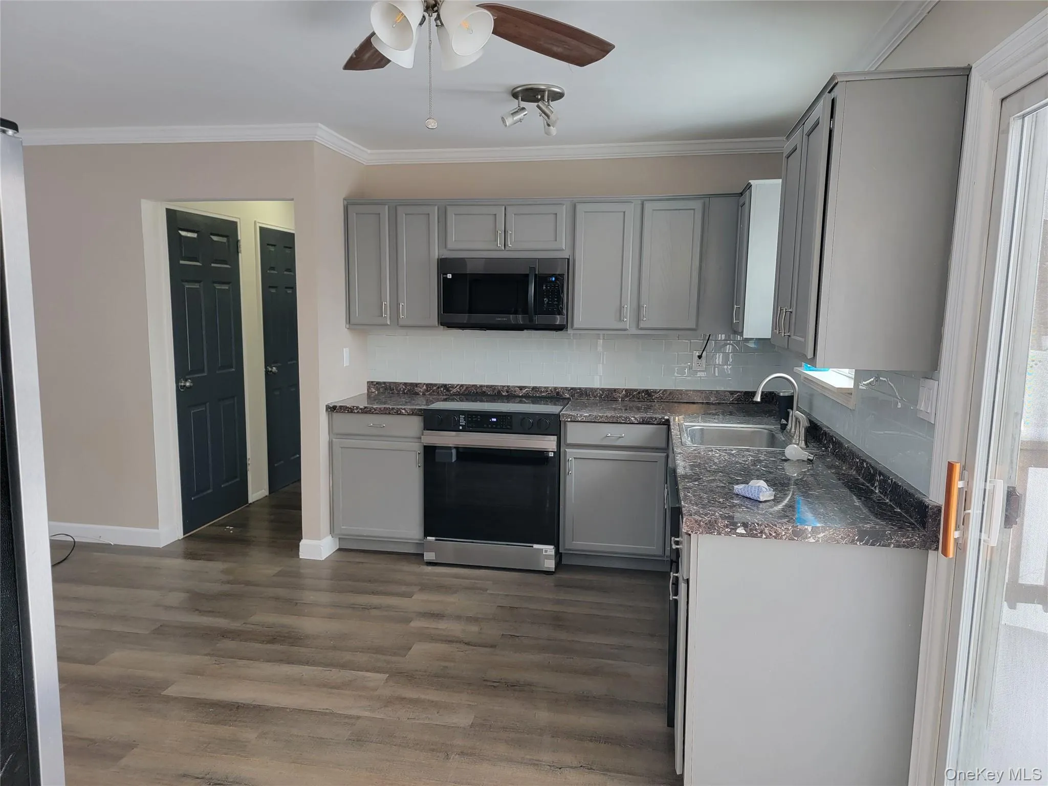 Kitchen featuring gray cabinets, electric stove, ornamental molding, stainless steel microwave, and ceiling fan Kitchen featuring gray cabinets, electric stove, ornamental molding, stainless steel microwave, and ceiling fan