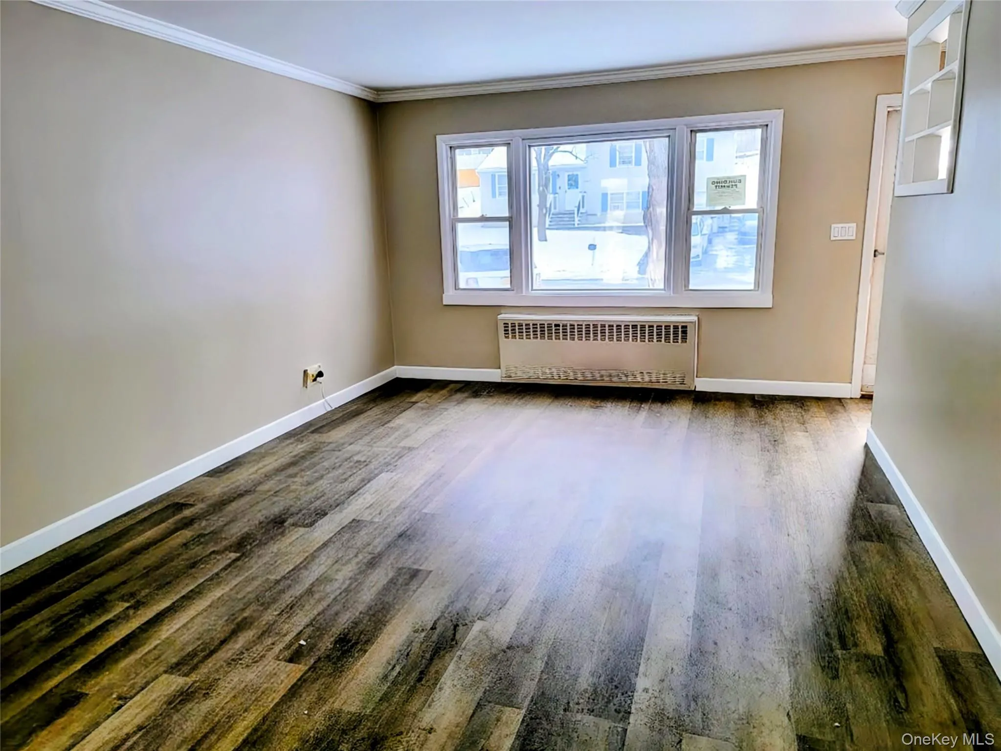 Unfurnished room featuring radiator, crown molding, and dark wood finished floors Unfurnished room featuring radiator, crown molding, and dark wood finished floors