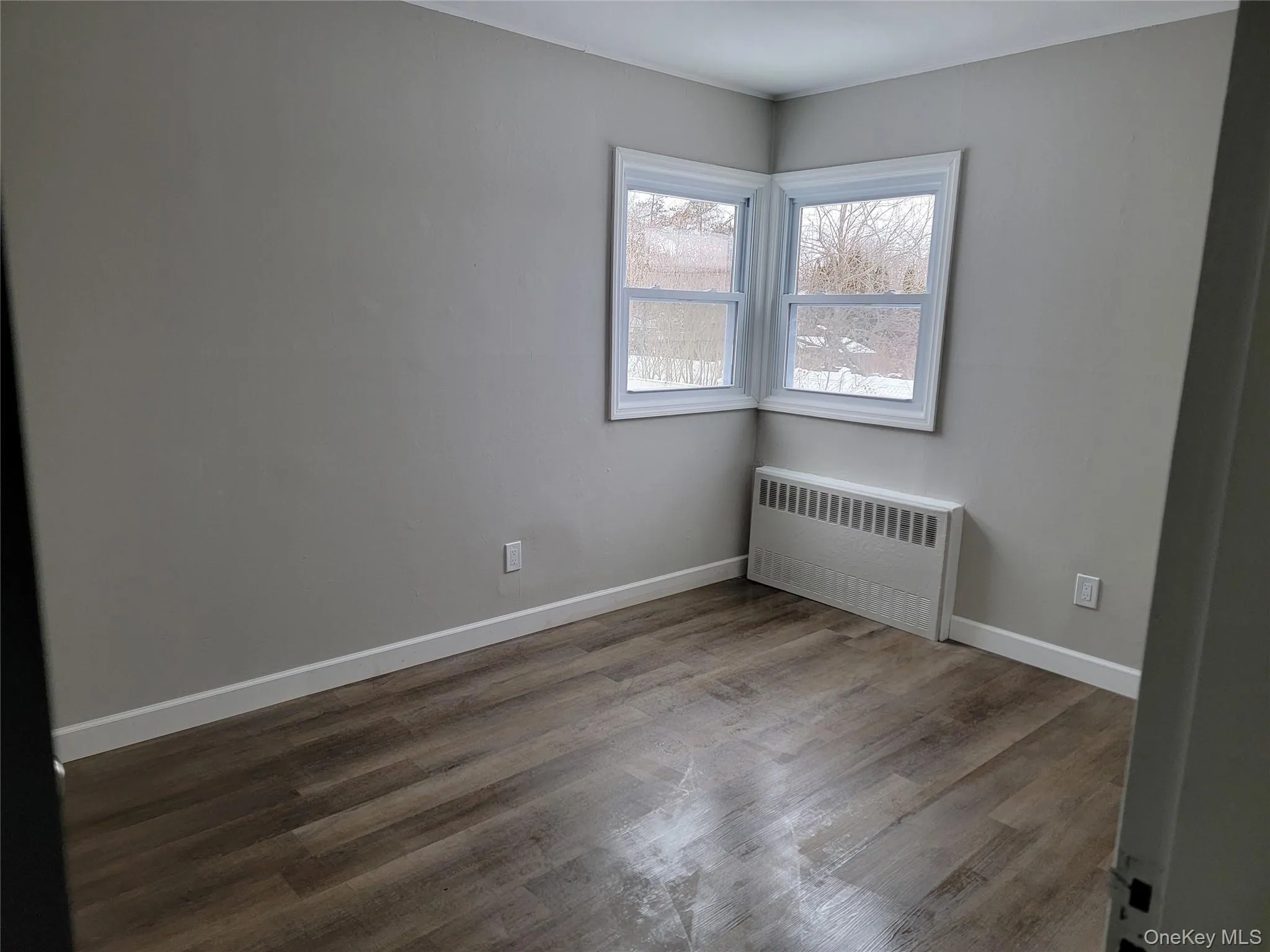 Spare room featuring radiator and light wood-style floors Spare room featuring radiator and light wood-style floors