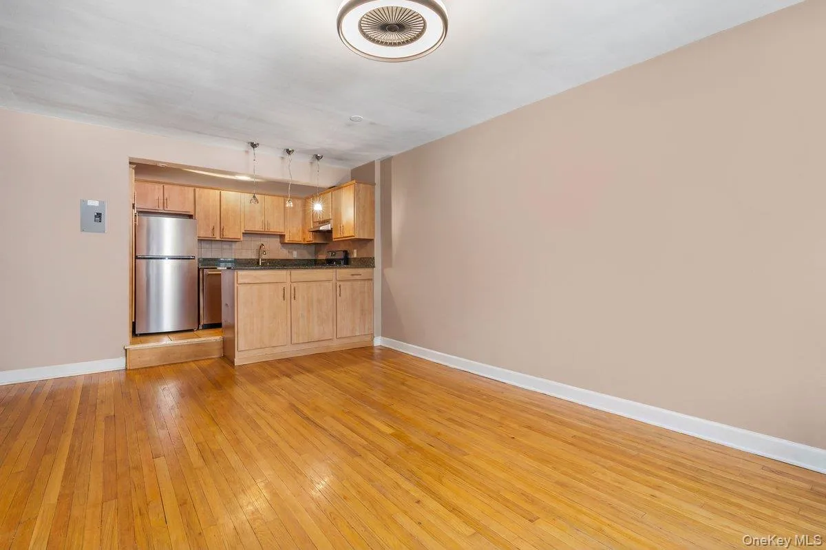 Kitchen featuring hanging light fixtures, open floor plan, stainless steel appliances, decorative backsplash, and light wood-type flooring Kitchen featuring hanging light fixtures, open floor plan, stainless steel appliances, decorative backsplash, and light wood-type flooring