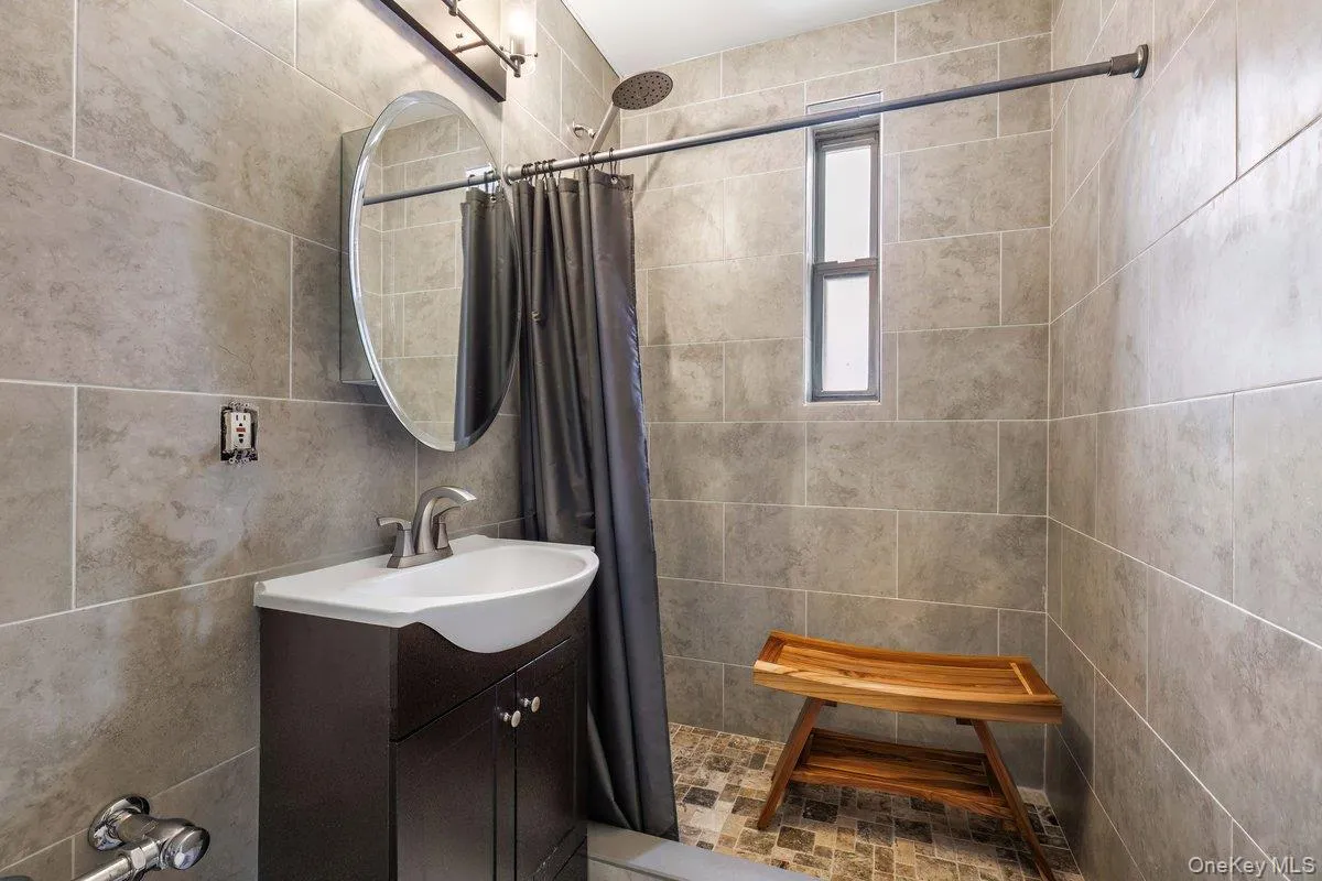 Full bathroom featuring vanity, a stall shower, and tile walls Full bathroom featuring vanity, a stall shower, and tile walls
