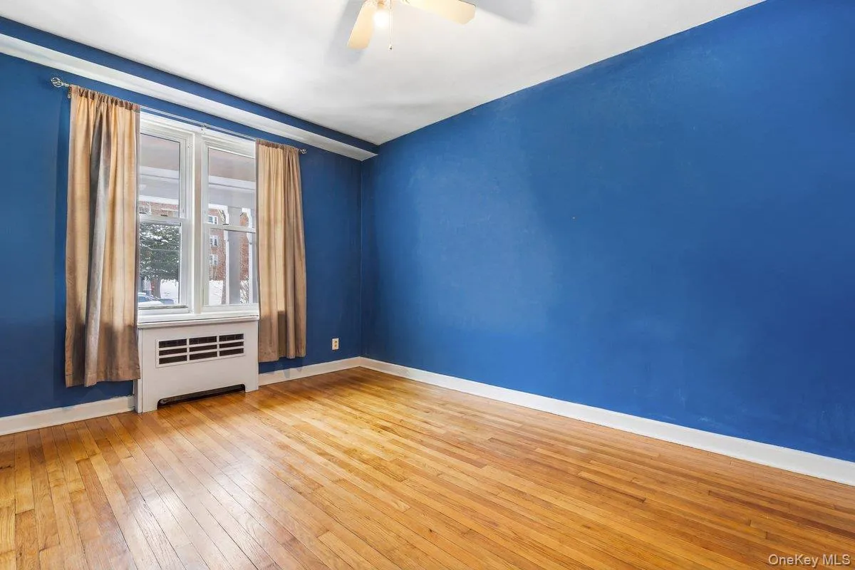 Spare room featuring radiator heating unit, light wood-type flooring, and a ceiling fan Spare room featuring radiator heating unit, light wood-type flooring, and a ceiling fan