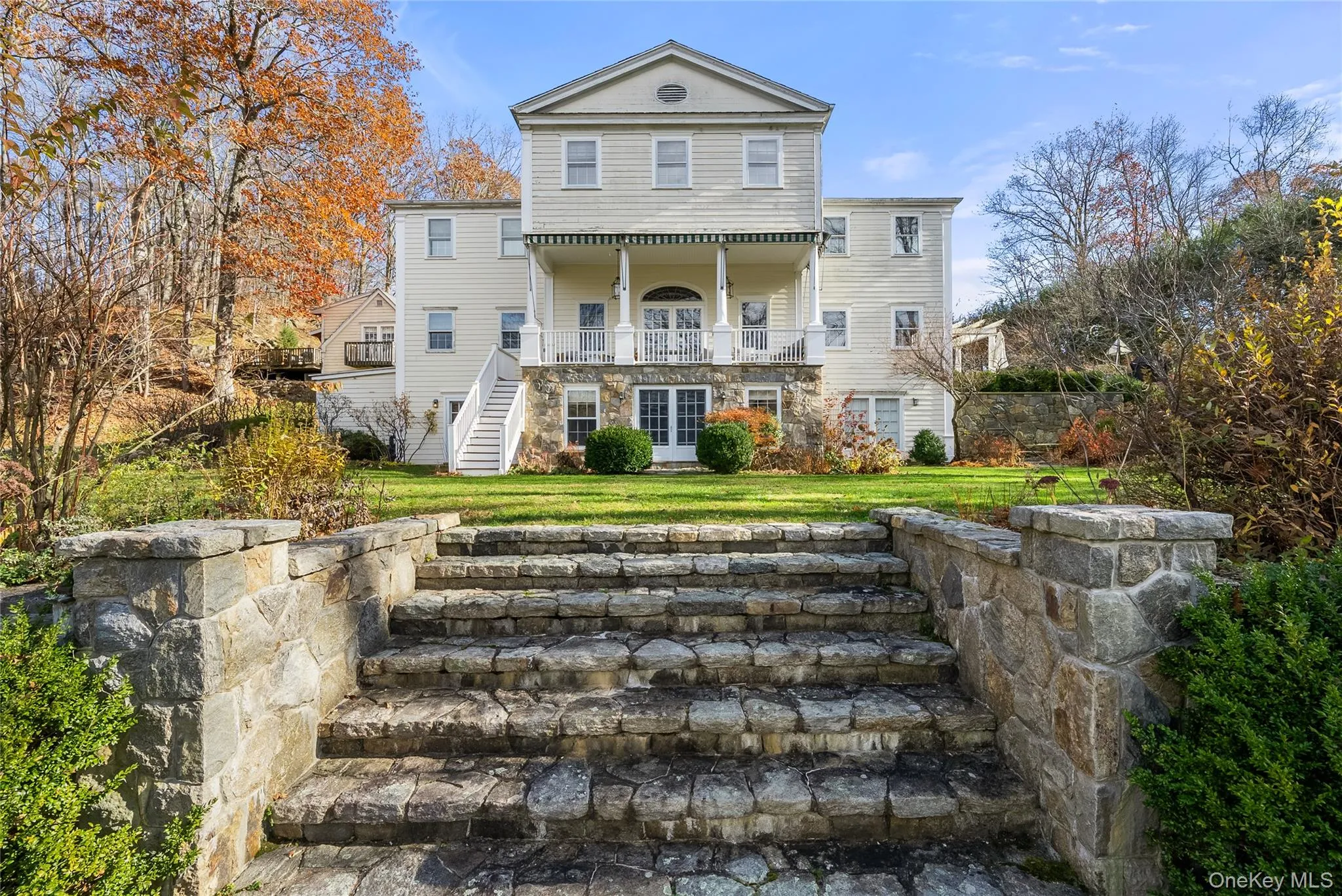 Rear view of house with stairs, a lawn, and a balcony Rear view of house with stairs, a lawn, and a balcony