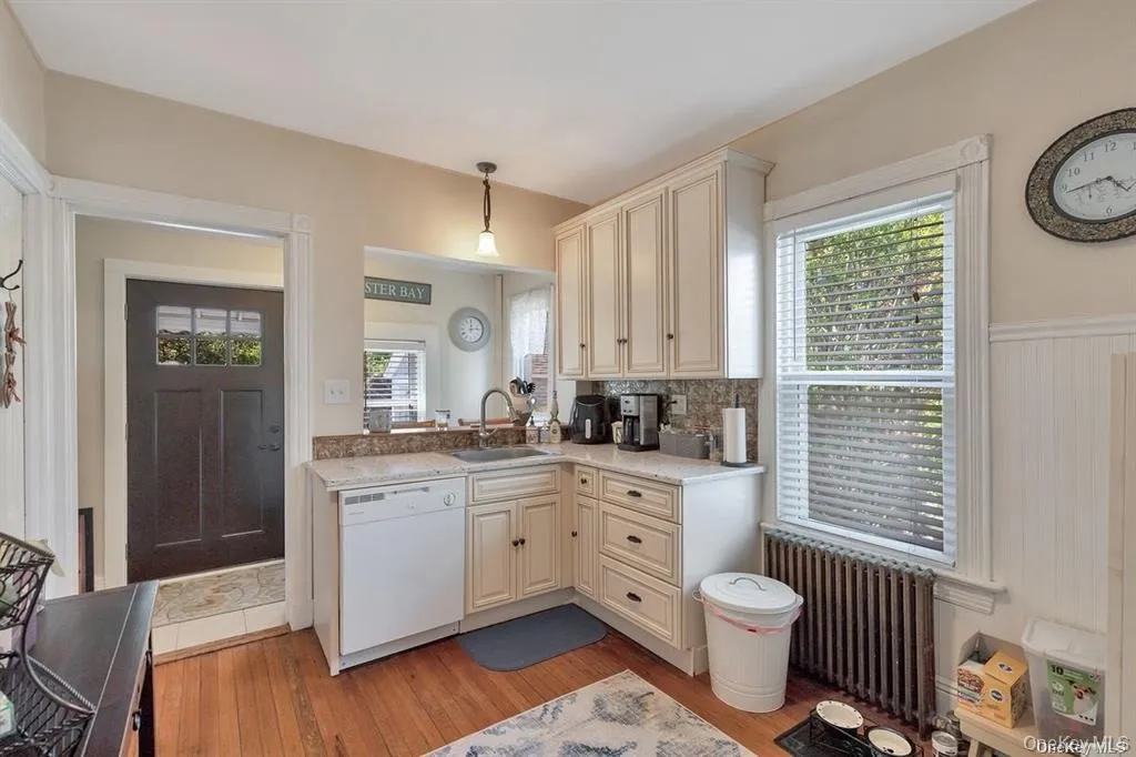 Kitchen with cream cabinetry, dishwasher, pendant lighting, radiator, and healthy amount of natural light Kitchen with cream cabinetry, dishwasher, pendant lighting, radiator, and healthy amount of natural light