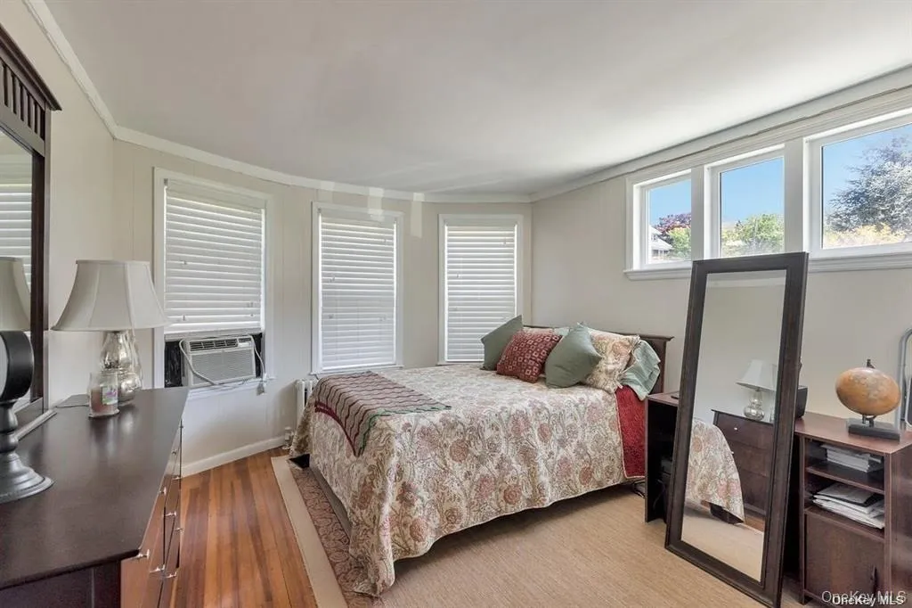 Bedroom featuring wood finished floors, ornamental molding, and cooling unit Bedroom featuring wood finished floors, ornamental molding, and cooling unit
