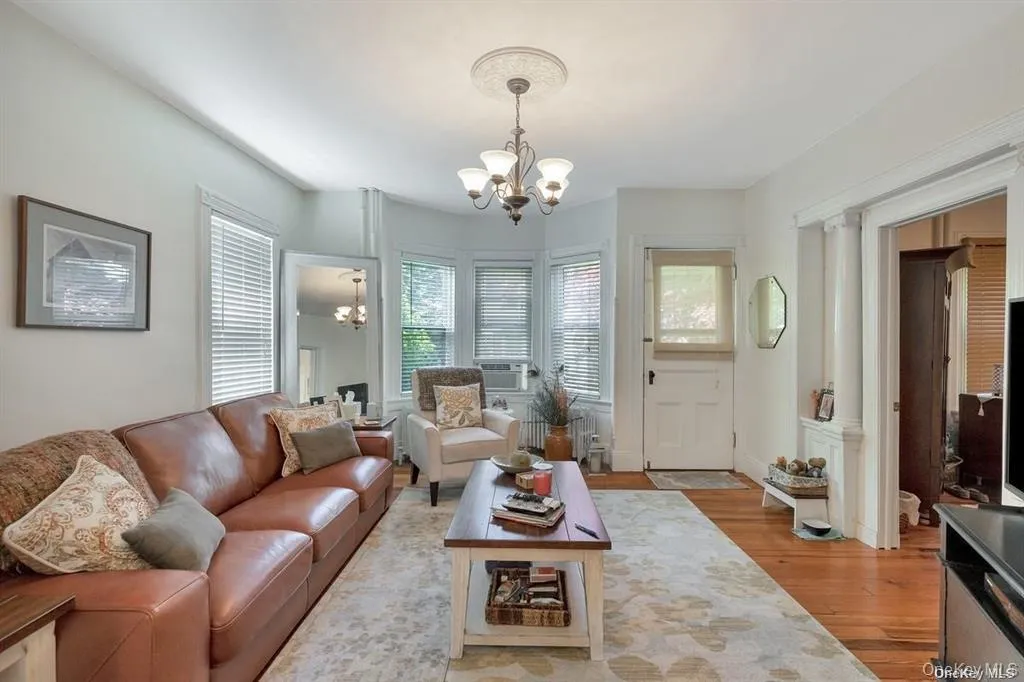 Living area featuring a chandelier, light wood-style floors, and radiator heating unit Living area featuring a chandelier, light wood-style floors, and radiator heating unit