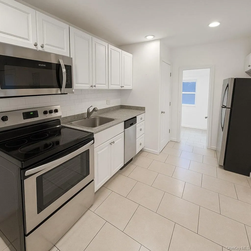 Kitchen with appliances with stainless steel finishes, white cabinetry, decorative backsplash, light tile patterned floors, and recessed lighting Kitchen with appliances with stainless steel finishes, white cabinetry, decorative backsplash, light tile patterned floors, and recessed lighting