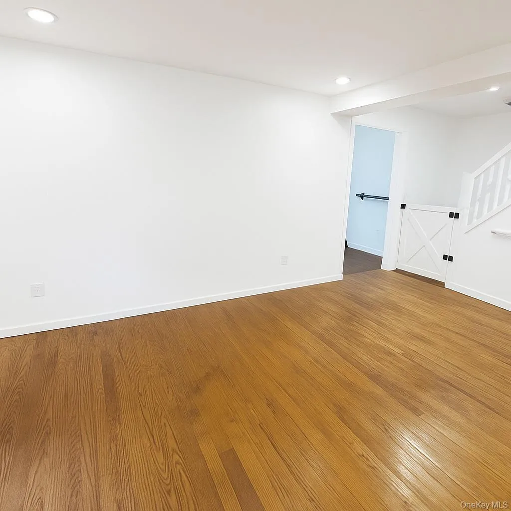 Unfurnished room with wood finished floors, recessed lighting, and stairs Unfurnished room with wood finished floors, recessed lighting, and stairs