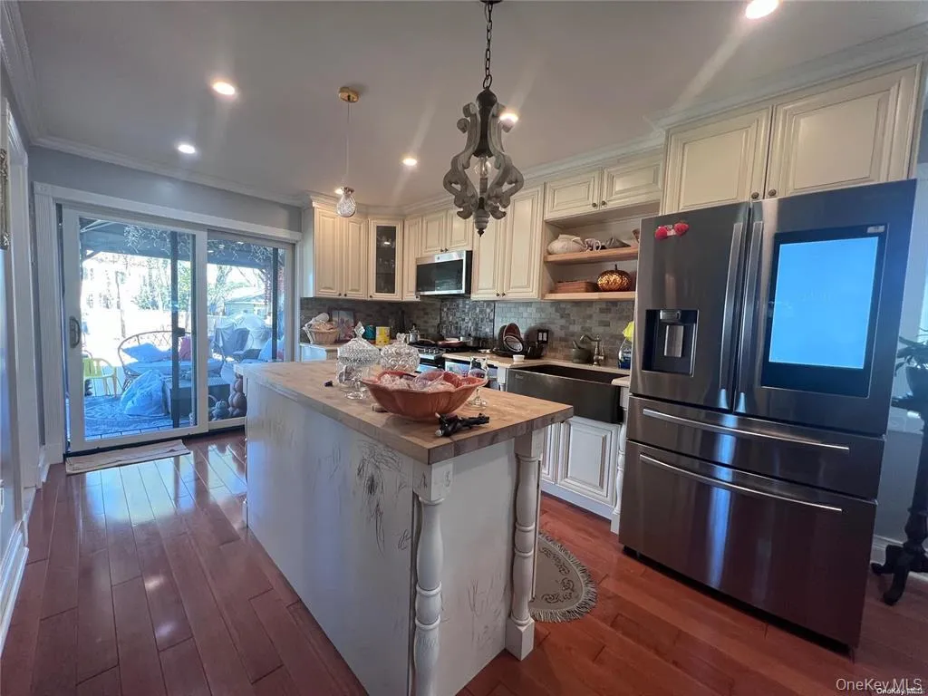 Kitchen with appliances with stainless steel finishes, crown molding, open shelves, recessed lighting, and hanging light fixtures Kitchen with appliances with stainless steel finishes, crown molding, open shelves, recessed lighting, and hanging light fixtures