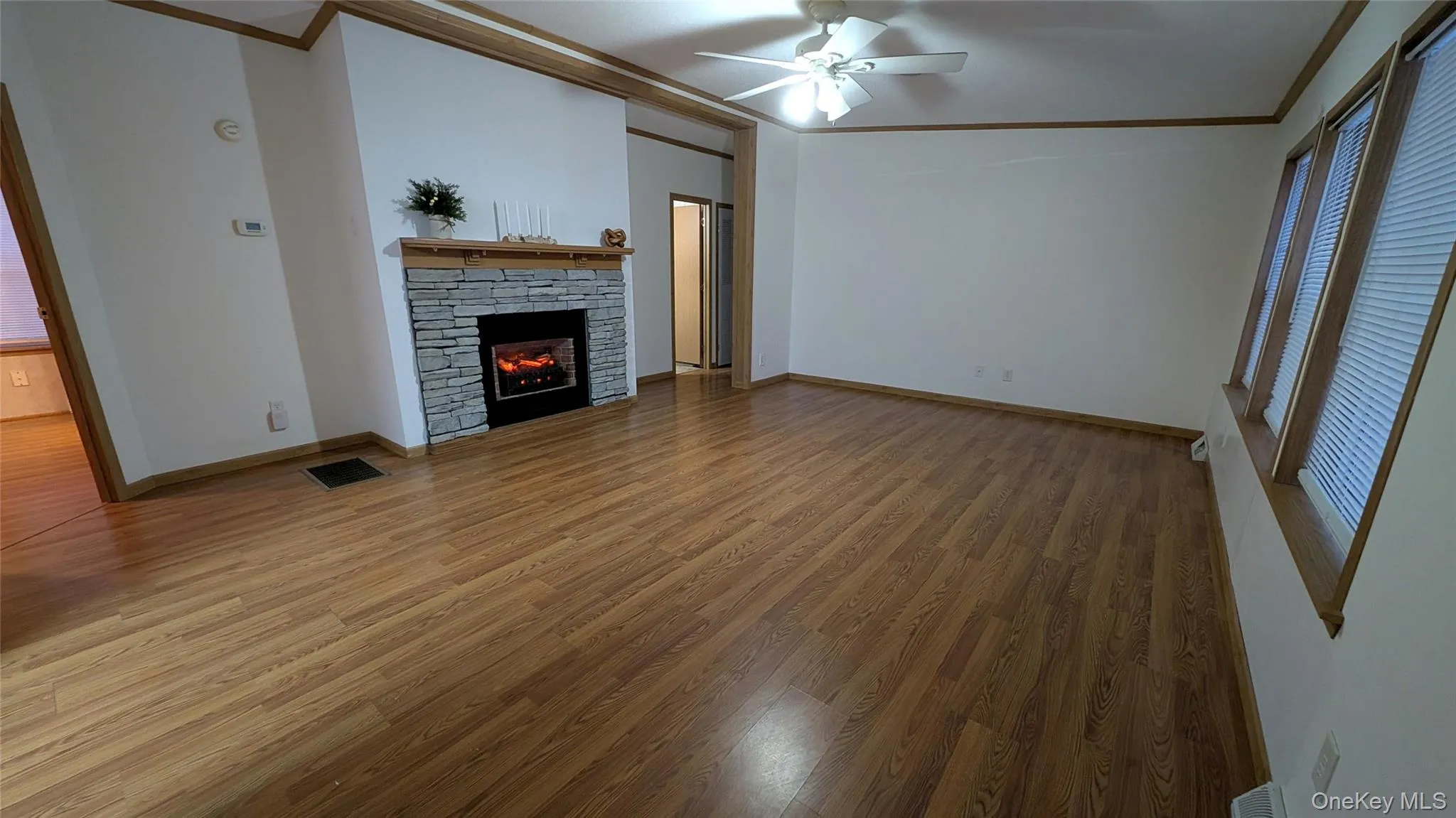Unfurnished living room featuring crown molding, light wood-style floors, a fireplace, and ceiling fan Unfurnished living room featuring crown molding, light wood-style floors, a fireplace, and ceiling fan