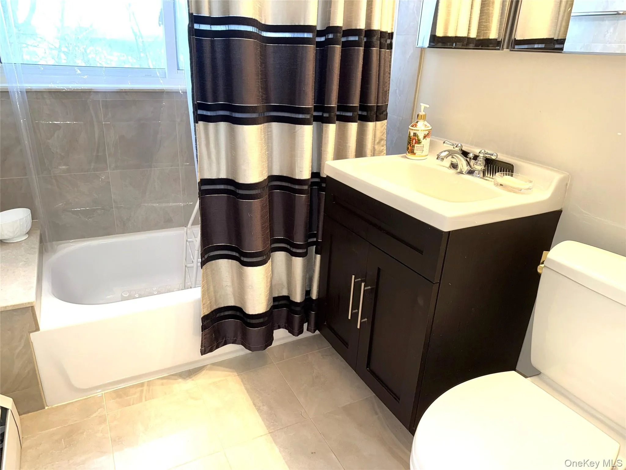 Bathroom featuring vanity, shower / tub combo with curtain, and light tile patterned floors Bathroom featuring vanity, shower / tub combo with curtain, and light tile patterned floors