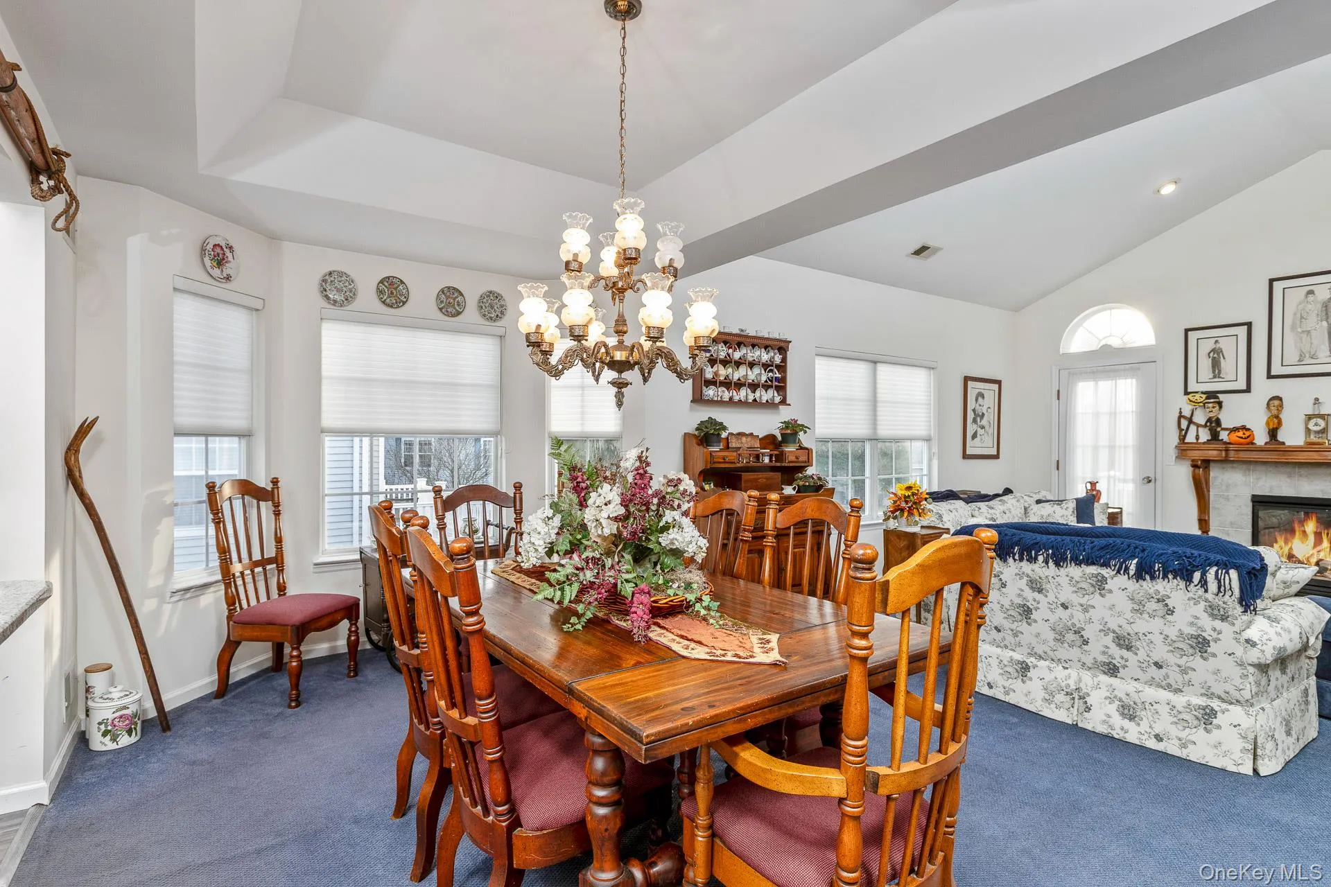 Dining room with a chandelier, dark carpet, lofted ceiling, and a fireplace Dining room with a chandelier, dark carpet, lofted ceiling, and a fireplace