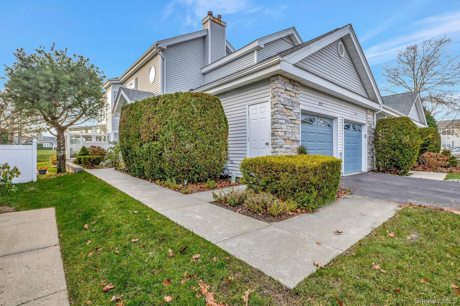 View of side of home with a yard, asphalt driveway, stone siding, a garage, and a chimney View of side of home with a yard, asphalt driveway, stone siding, a garage, and a chimney