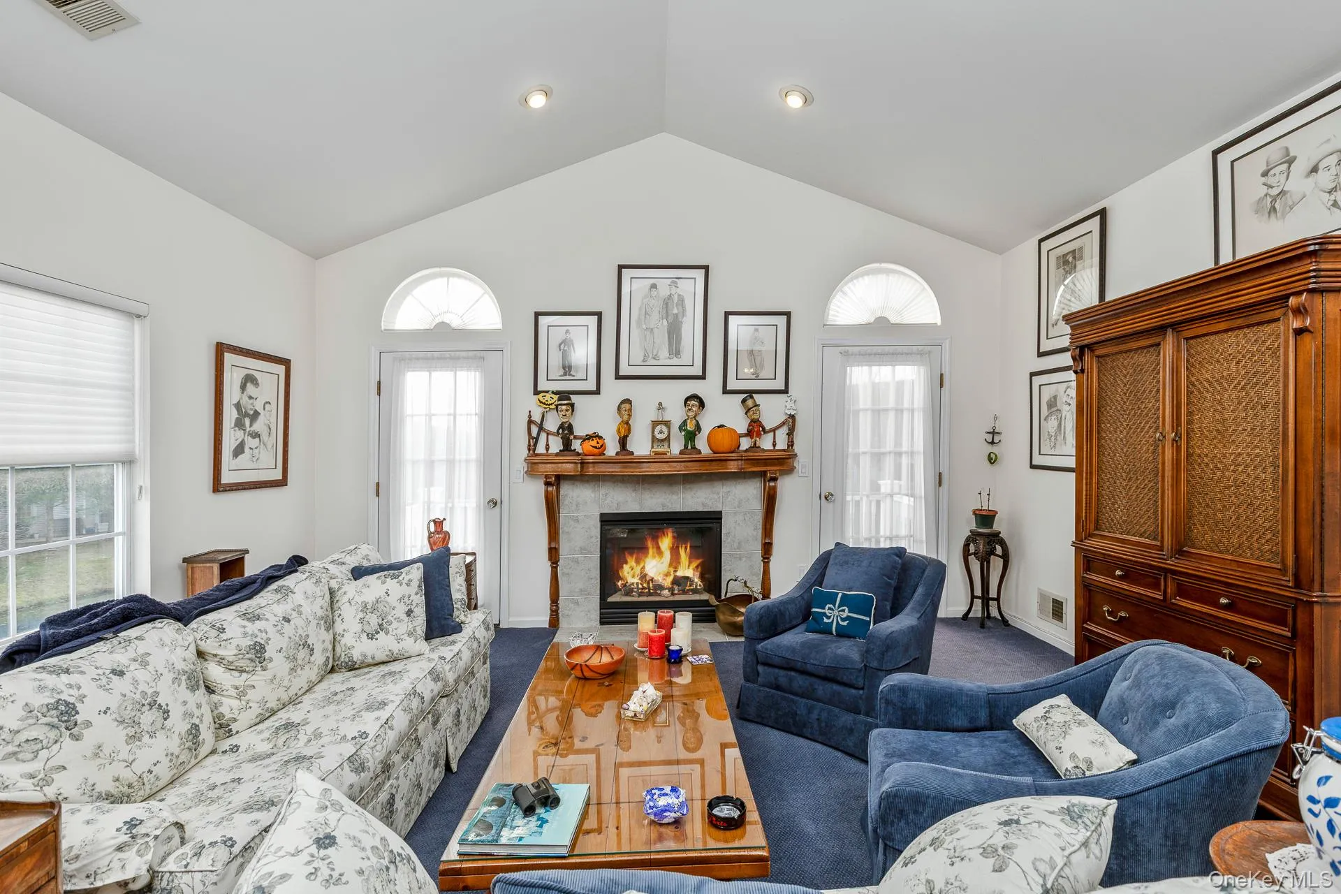 Living area with a tiled fireplace, plenty of natural light, carpet floors, and high vaulted ceiling Living area with a tiled fireplace, plenty of natural light, carpet floors, and high vaulted ceiling