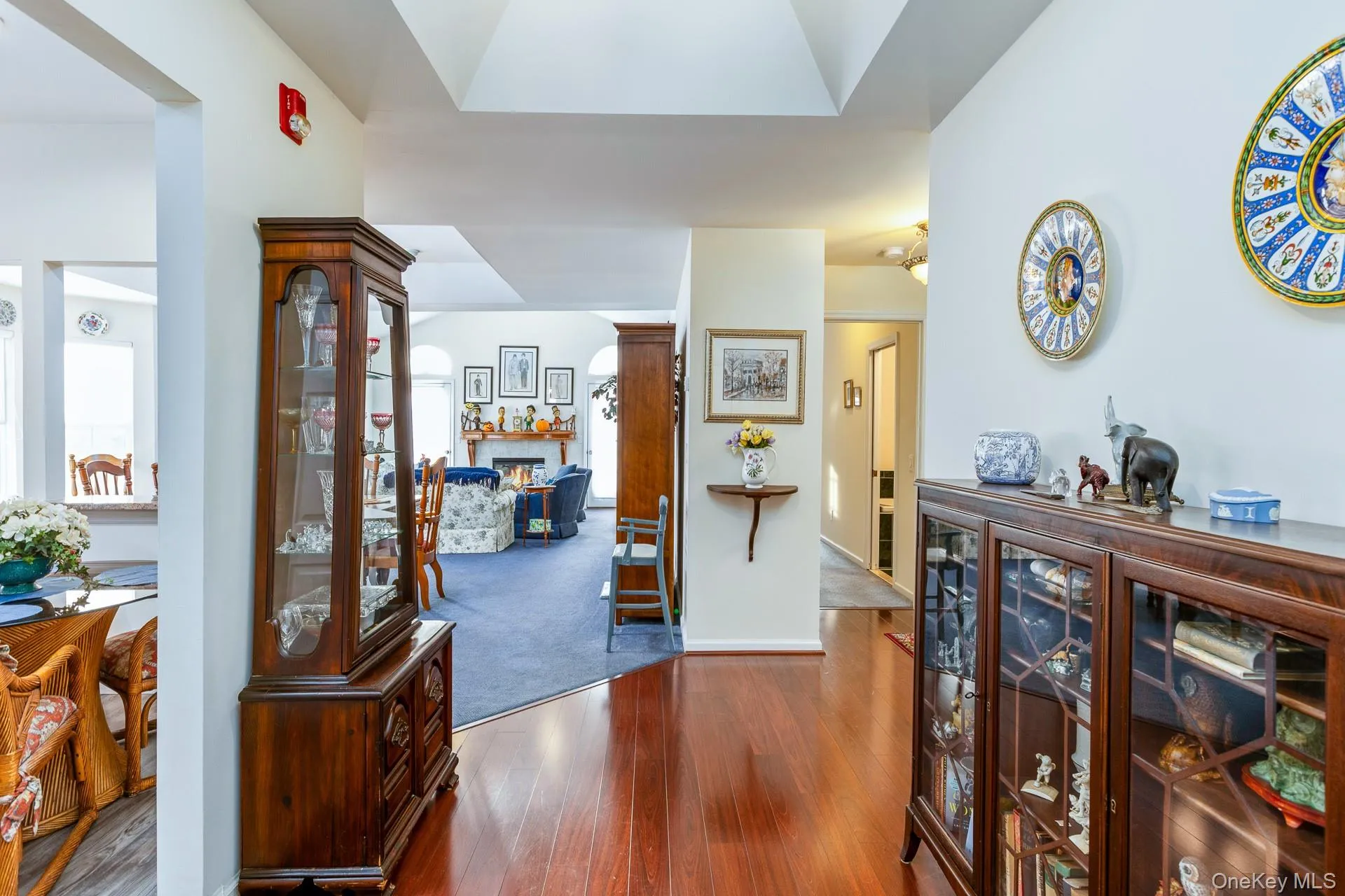 Foyer with dark wood-style floors, a warm lit fireplace, and decorative columns Foyer with dark wood-style floors, a warm lit fireplace, and decorative columns