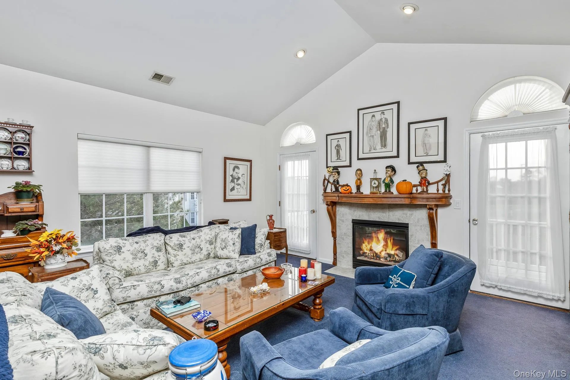 Carpeted living area featuring a fireplace and high vaulted ceiling Carpeted living area featuring a fireplace and high vaulted ceiling