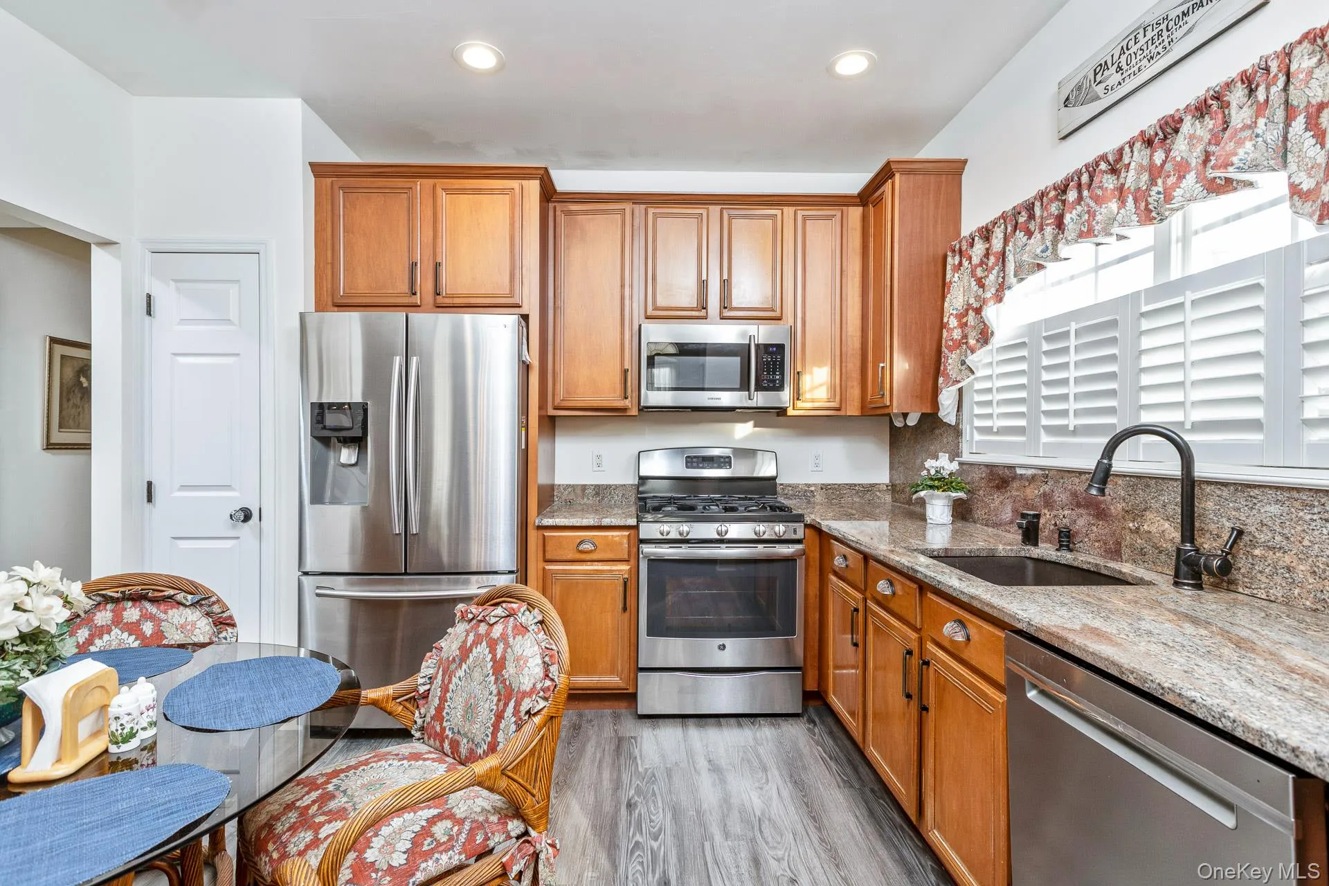 Kitchen featuring light stone countertops, appliances with stainless steel finishes, brown cabinets, light wood-style floors, and recessed lighting Kitchen featuring light stone countertops, appliances with stainless steel finishes, brown cabinets, light wood-style floors, and recessed lighting