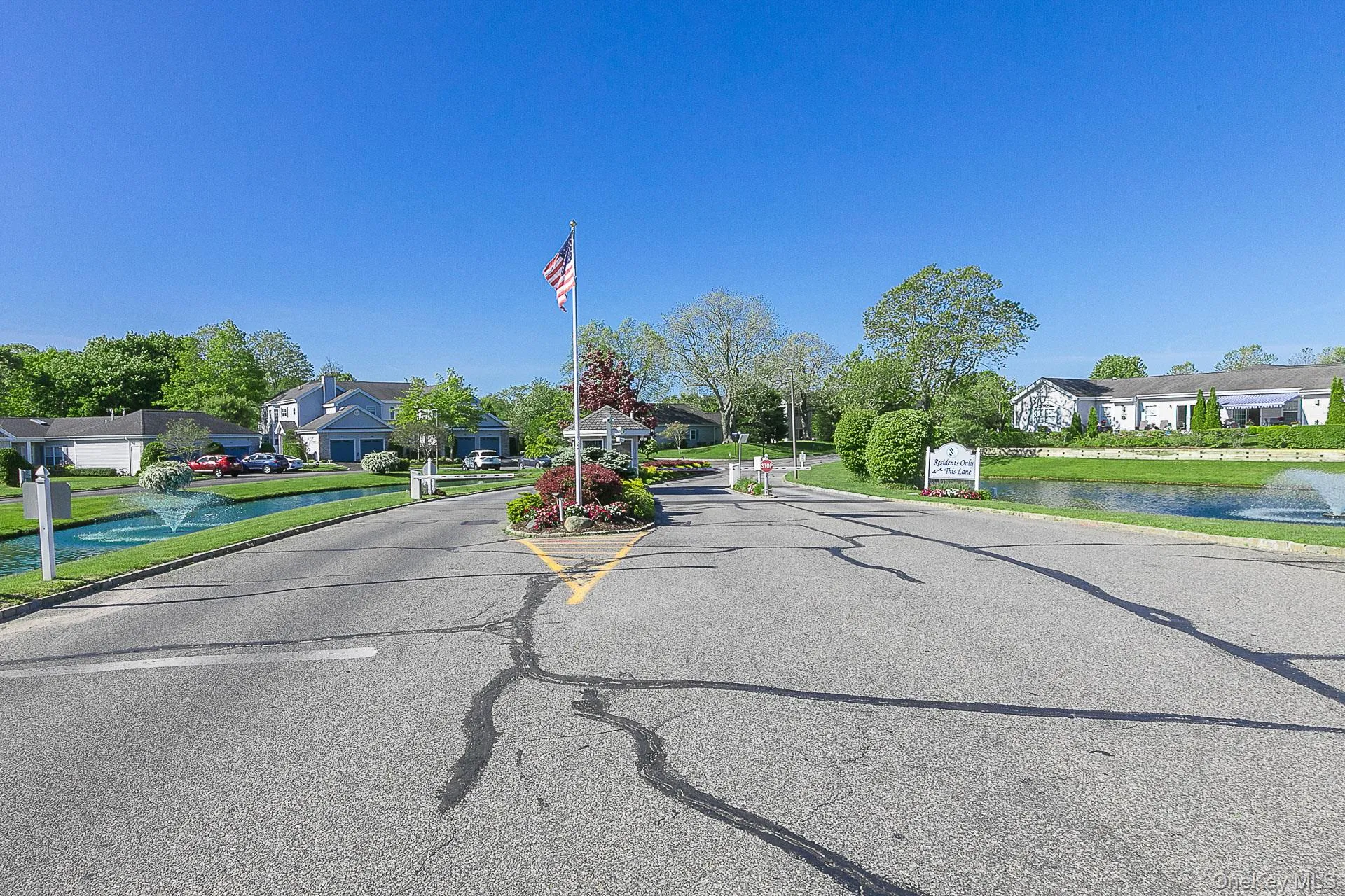 View of asphalt road featuring a residential view, a water view, and curbs View of asphalt road featuring a residential view, a water view, and curbs