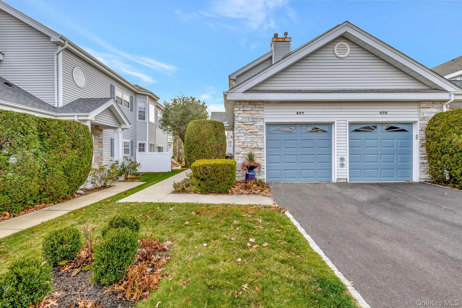 View of front of home featuring asphalt driveway, stone siding, a chimney, a front lawn, and a garage View of front of home featuring asphalt driveway, stone siding, a chimney, a front lawn, and a garage